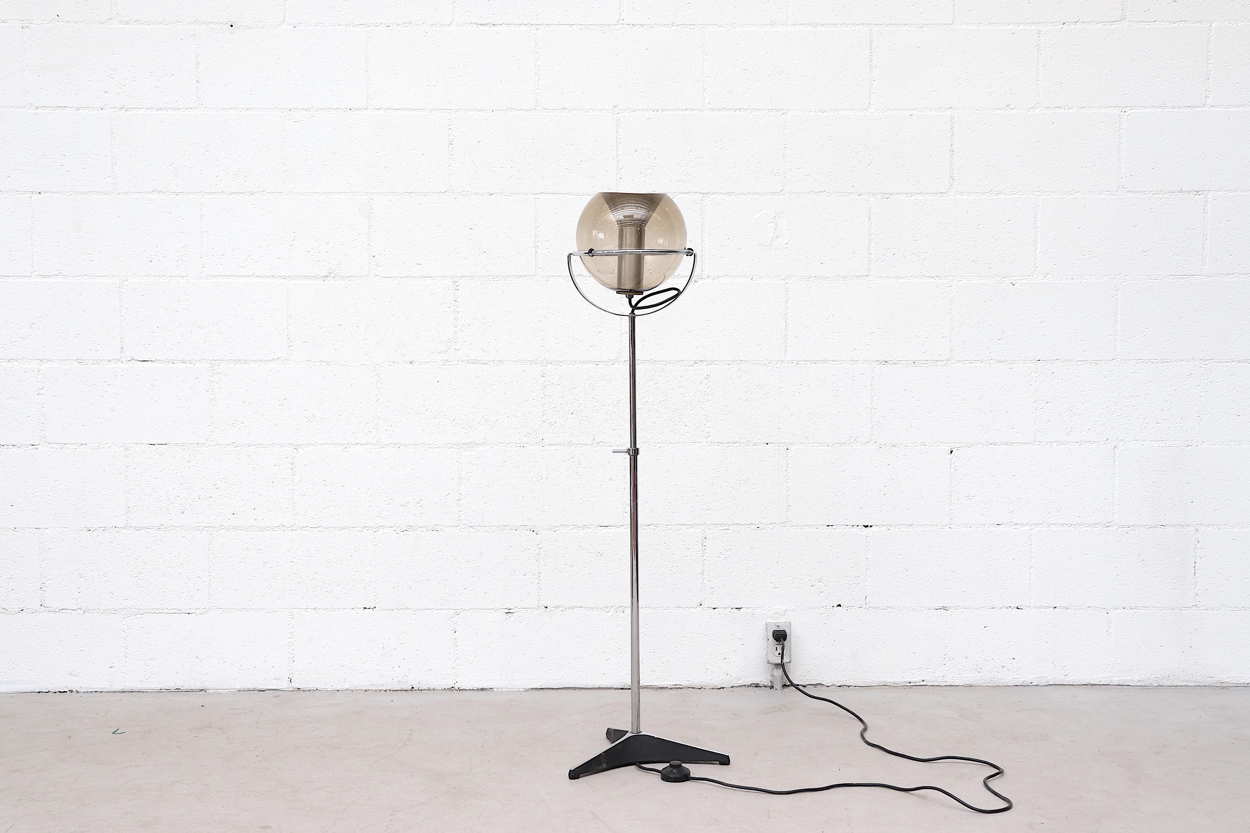 Amazing 1960s RAAK glass globe floor lamp with tubular chrome stem and black metal base. Designed by Frank Ligtelijn, for RAAK, 1962. The Lamp has a detached smoked glass globe shade and height adjustable stem. In original condition with some wear