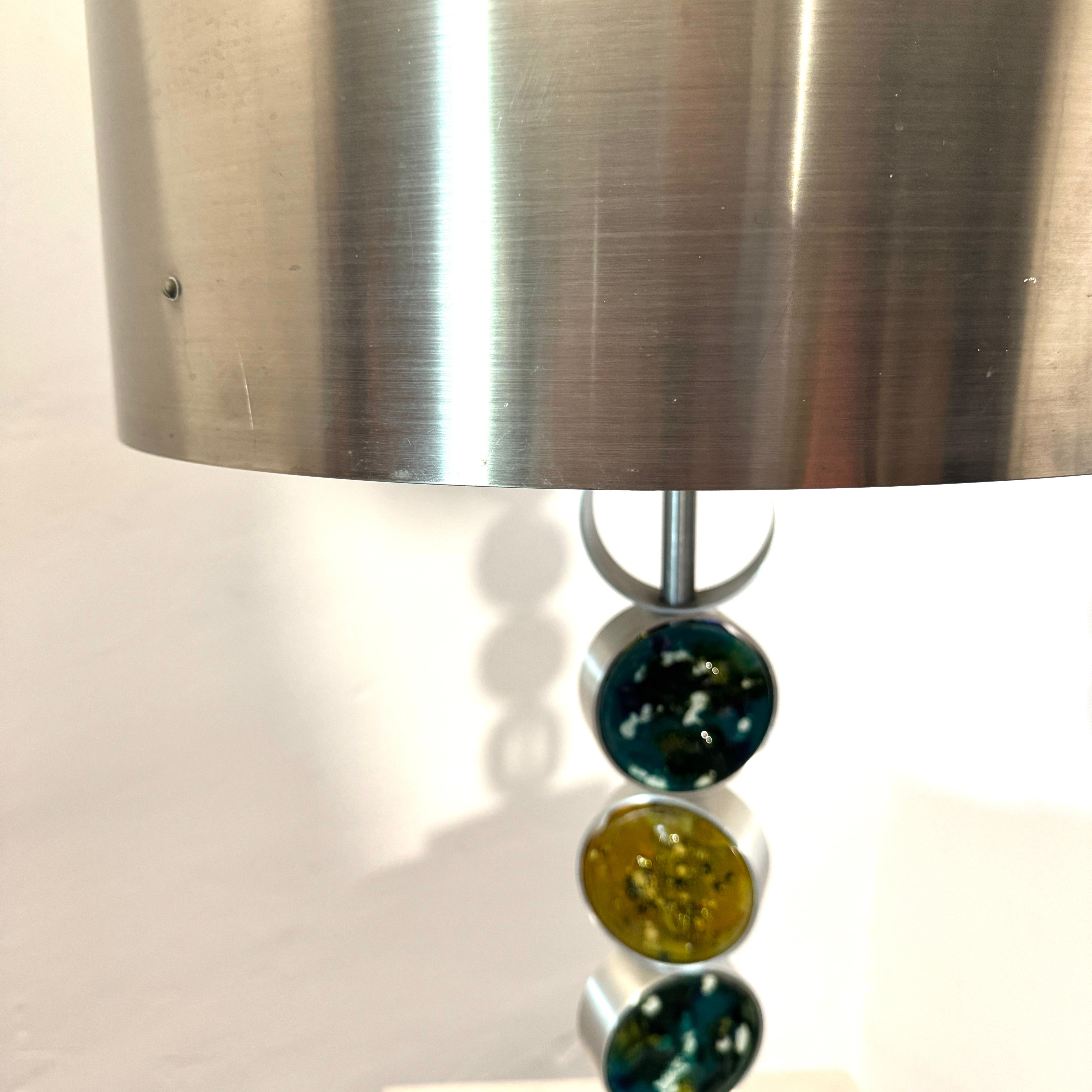 This large vintage table lamp by Nanny Still for RAAK Amsterdam, combines Modernist & Brutalist influences its design. 

Complemented with the addition of handmade coloured glass panels that soften the look and add glamour. 
It literally makes a