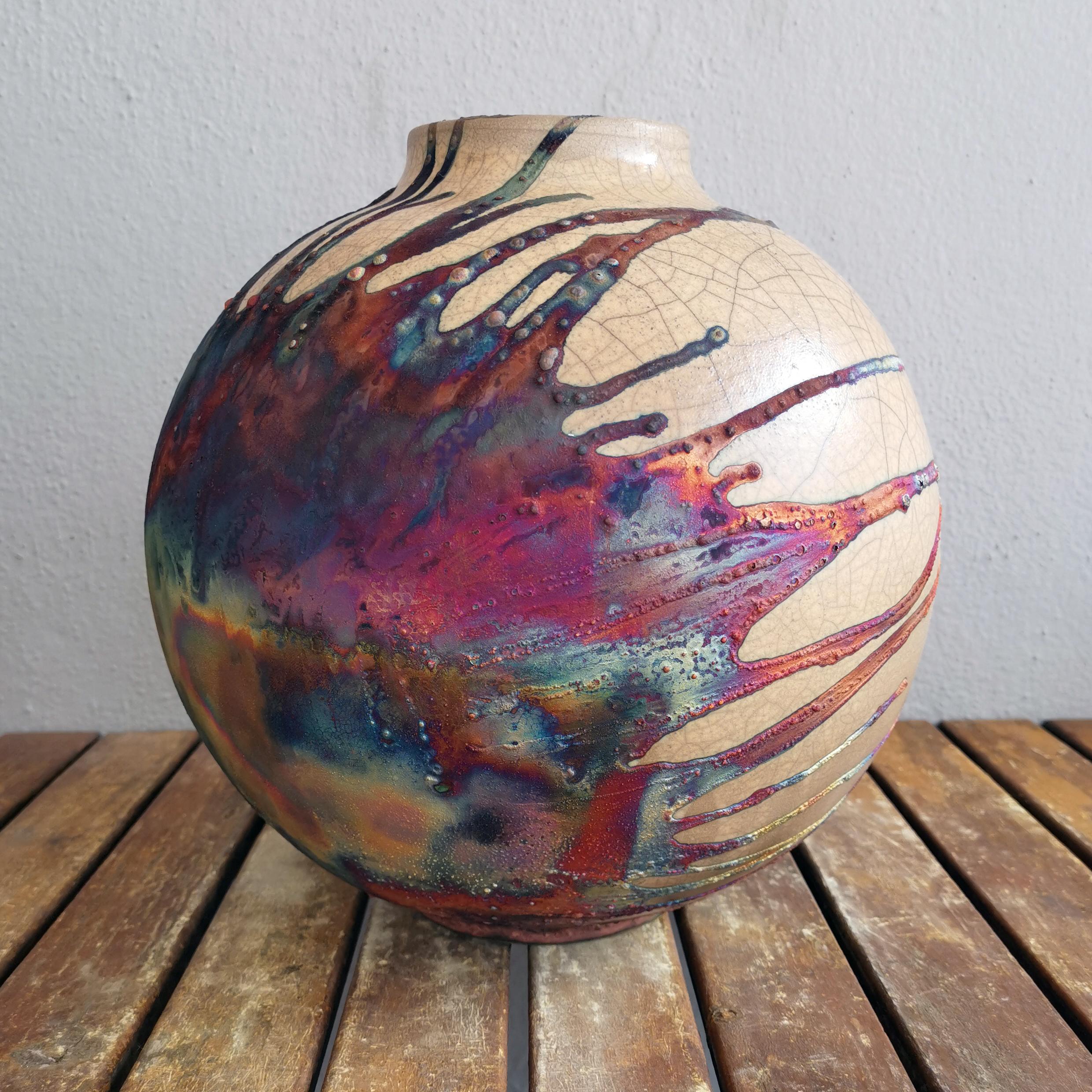 A mesmerizing sight to behold as soon as the rainbow-like patinas catch your eye. This globe vase is a round, capacious piece produced using the Raku technique, resulting in a beautiful unpredictable finish. This vase would be the perfect