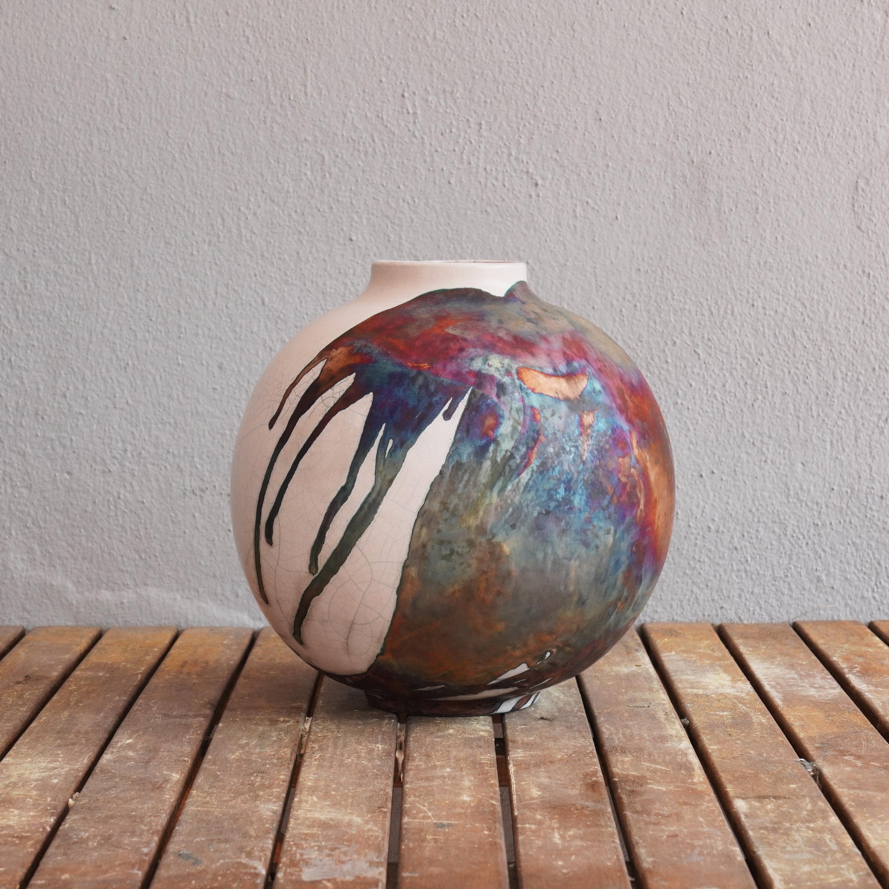 The Large Raku fired vase centerpiece Series by RAAQUU.

A mesmerizing sight to behold as soon as the rainbow-like patinas catch your eye. This Globe Vase is a round, capacious piece produced using the Raku technique, resulting in a beautiful