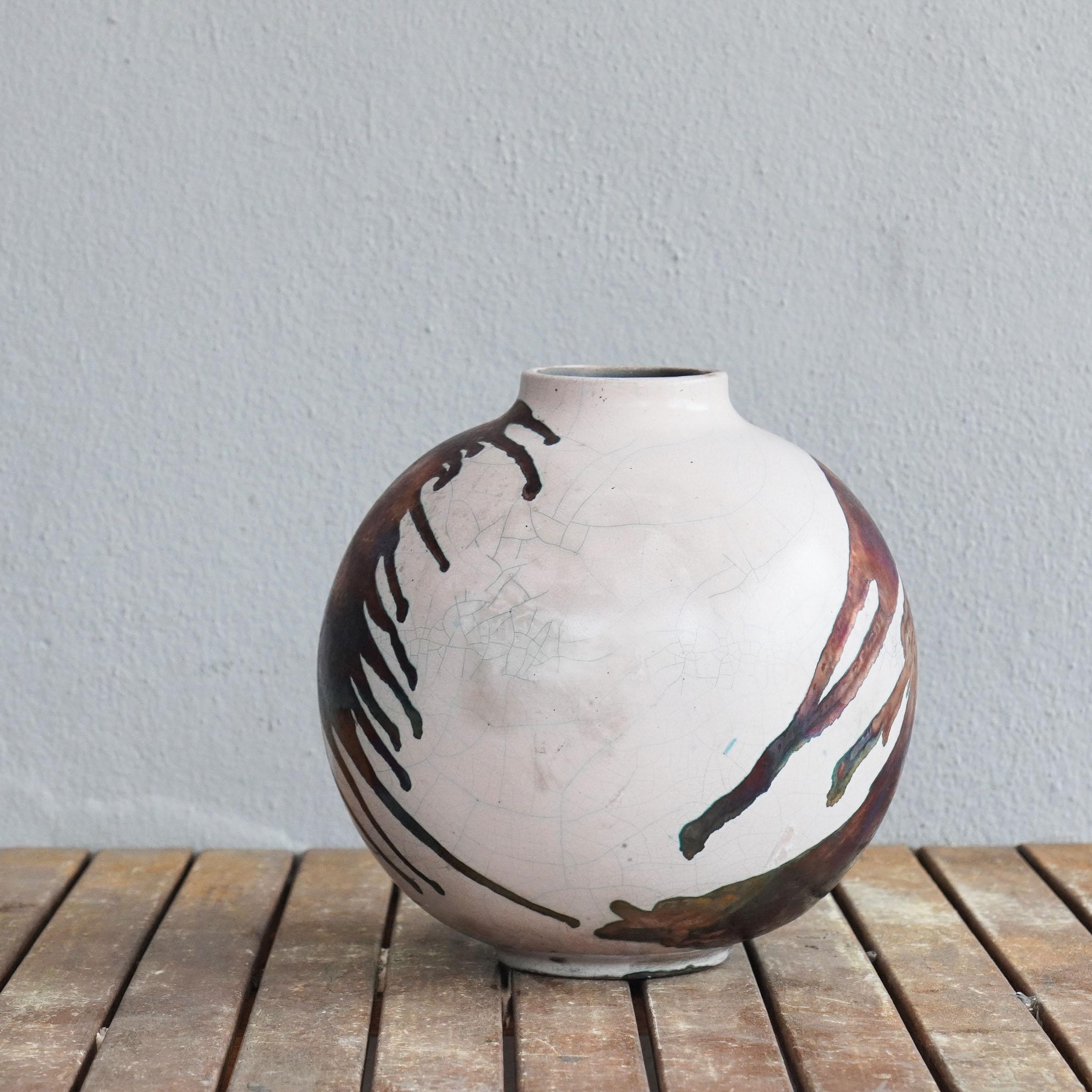 A mesmerizing sight to behold as soon as the rainbow-like patinas catch your eye. This Globe Vase is a round, capacious piece produced using the Raku technique, resulting in a beautiful unpredictable finish. This vase would be the perfect