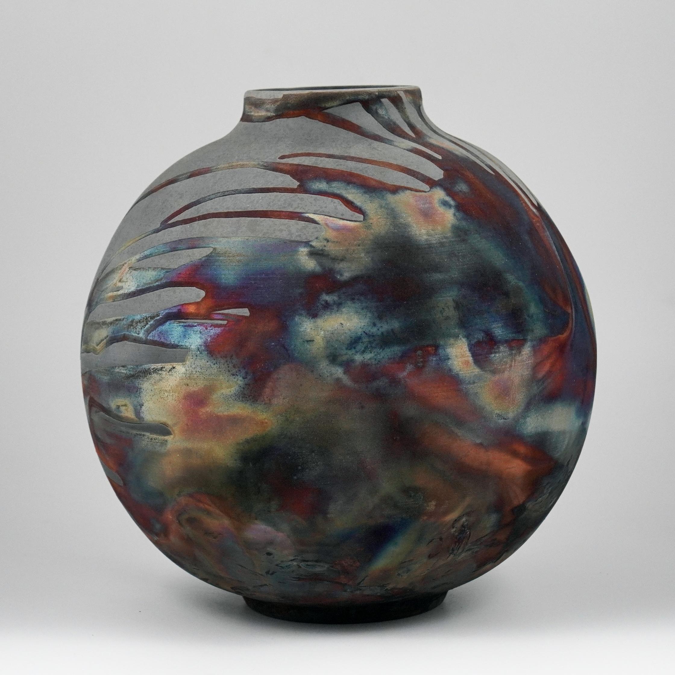A mesmerizing sight to behold as soon as the rainbow-like patinas catch your eye. This Globe Vase is a round, capacious piece produced using the Raku technique, resulting in a beautiful unpredictable finish. This vase would be the perfect