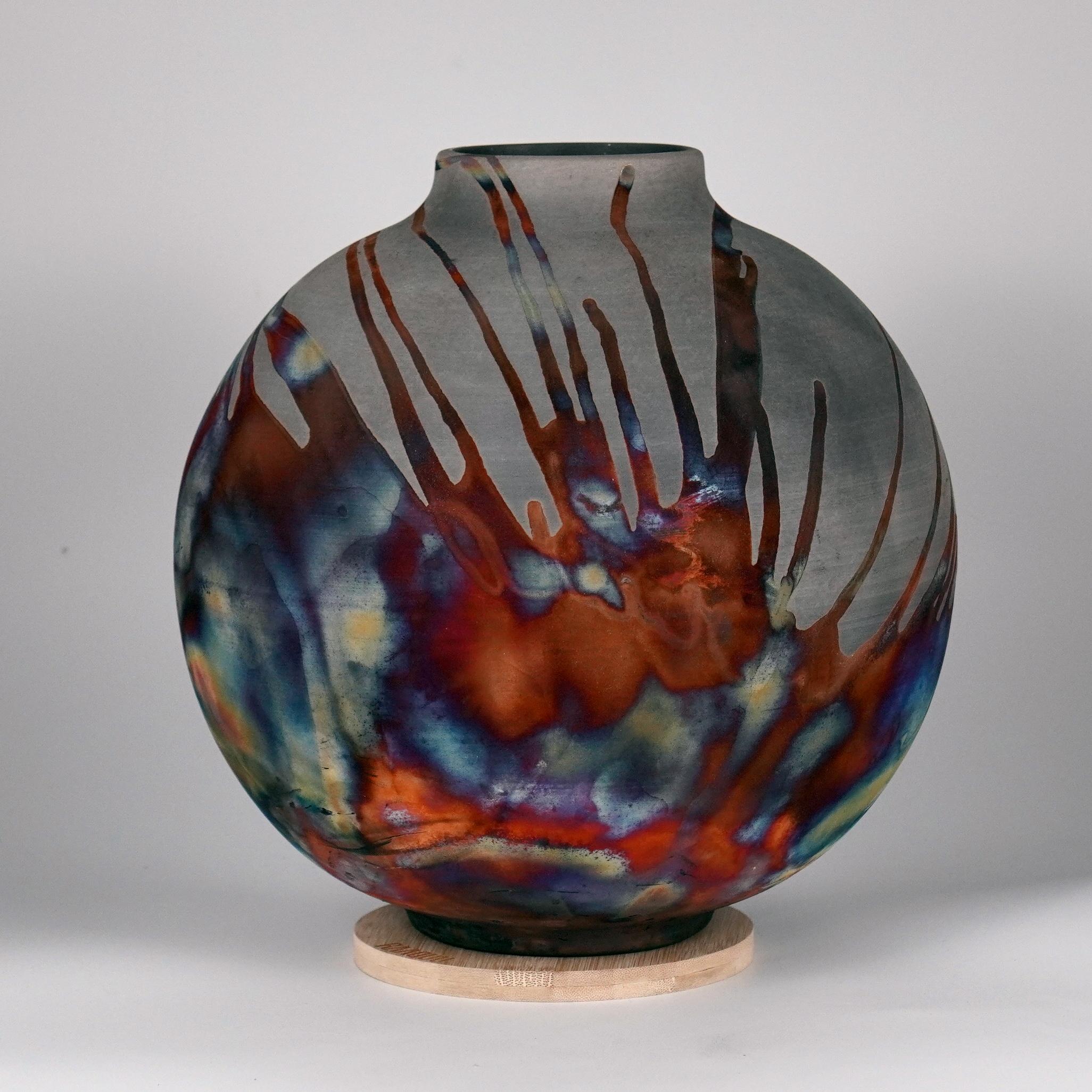 A mesmerizing sight to behold as soon as the rainbow-like patinas catch your eye. This Globe Vase is a round, capacious piece produced using the Raku technique, resulting in a beautiful unpredictable finish. This vase would be the perfect