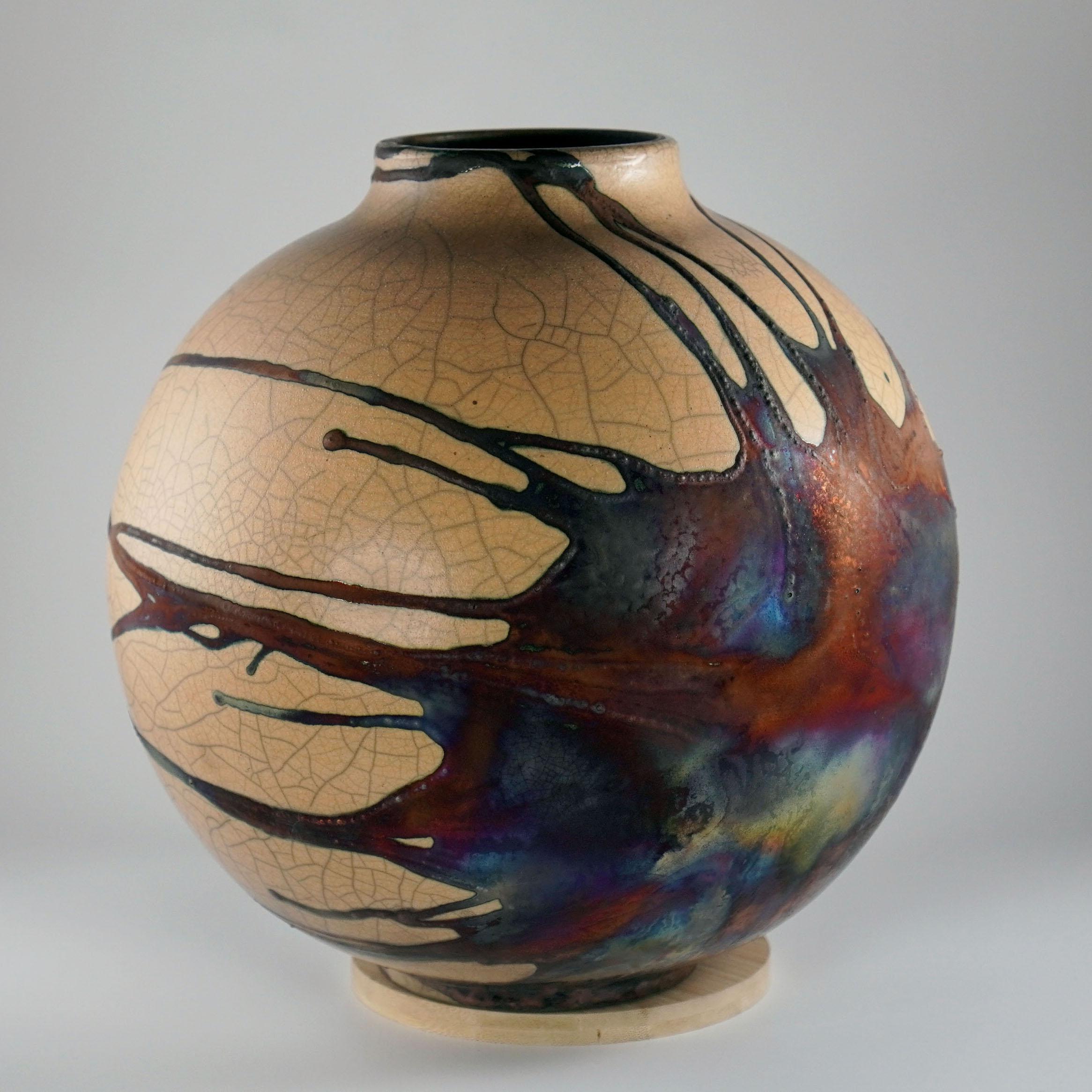 A mesmerizing sight to behold as soon as the rainbow-like patinas catch your eye. This Globe Vase is a round, capacious piece produced using the Raku technique, resulting in a beautiful unpredictable finish. This vase would be the perfect