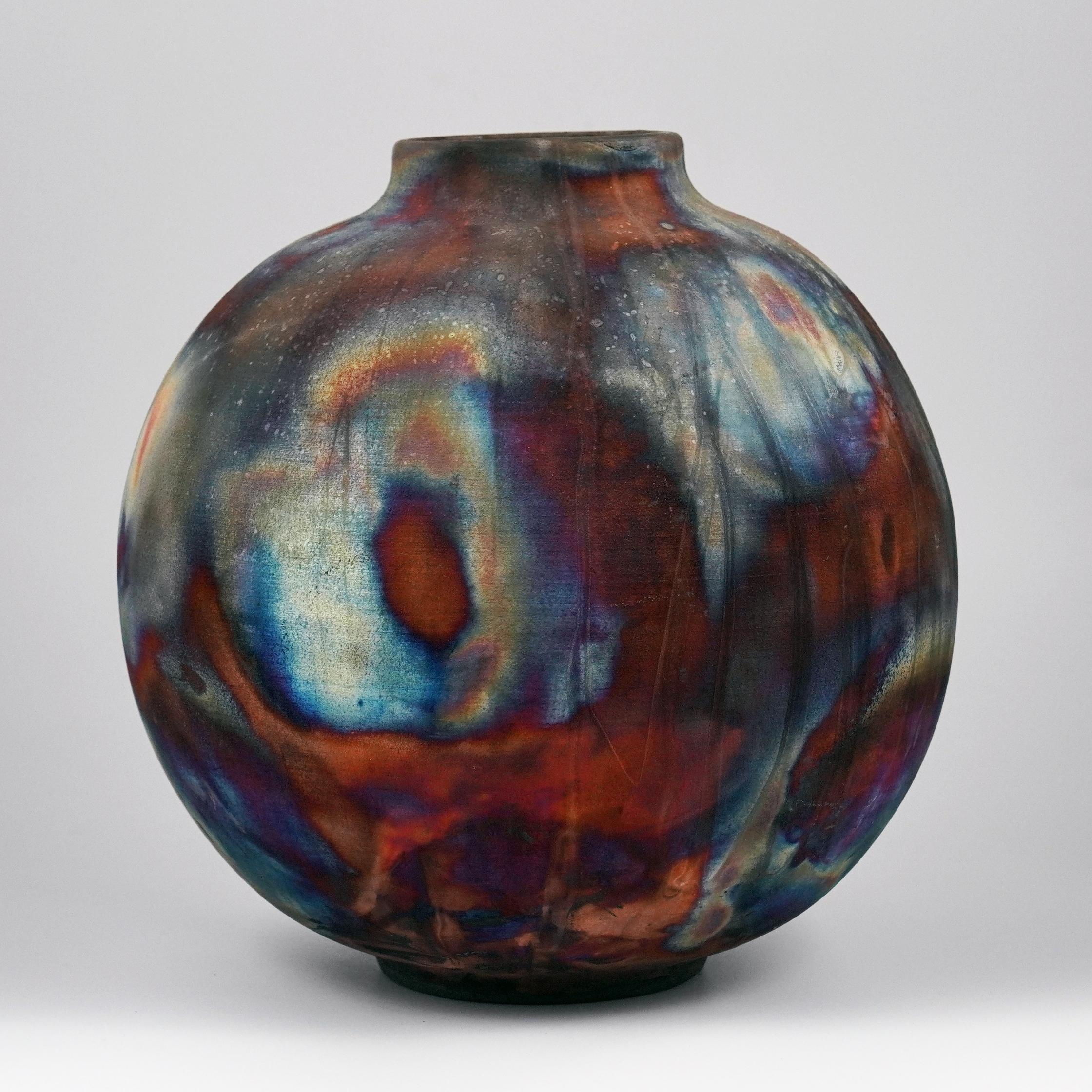 A mesmerizing sight to behold as soon as the rainbow-like patinas catch your eye. This Globe Vase is a round, capacious piece produced using the Raku technique, resulting in a beautiful unpredictable finish. This vase would be the perfect