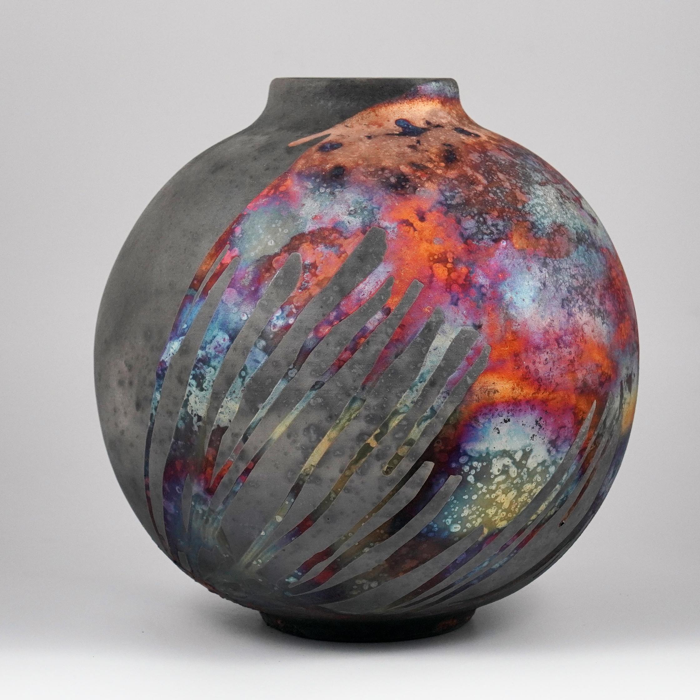 A mesmerizing sight to behold as soon as the rainbow-like patinas catch your eye. This Globe Vase is a round, capacious piece produced using the Raku technique, resulting in a beautiful unpredictable finish. This vase would be the perfect