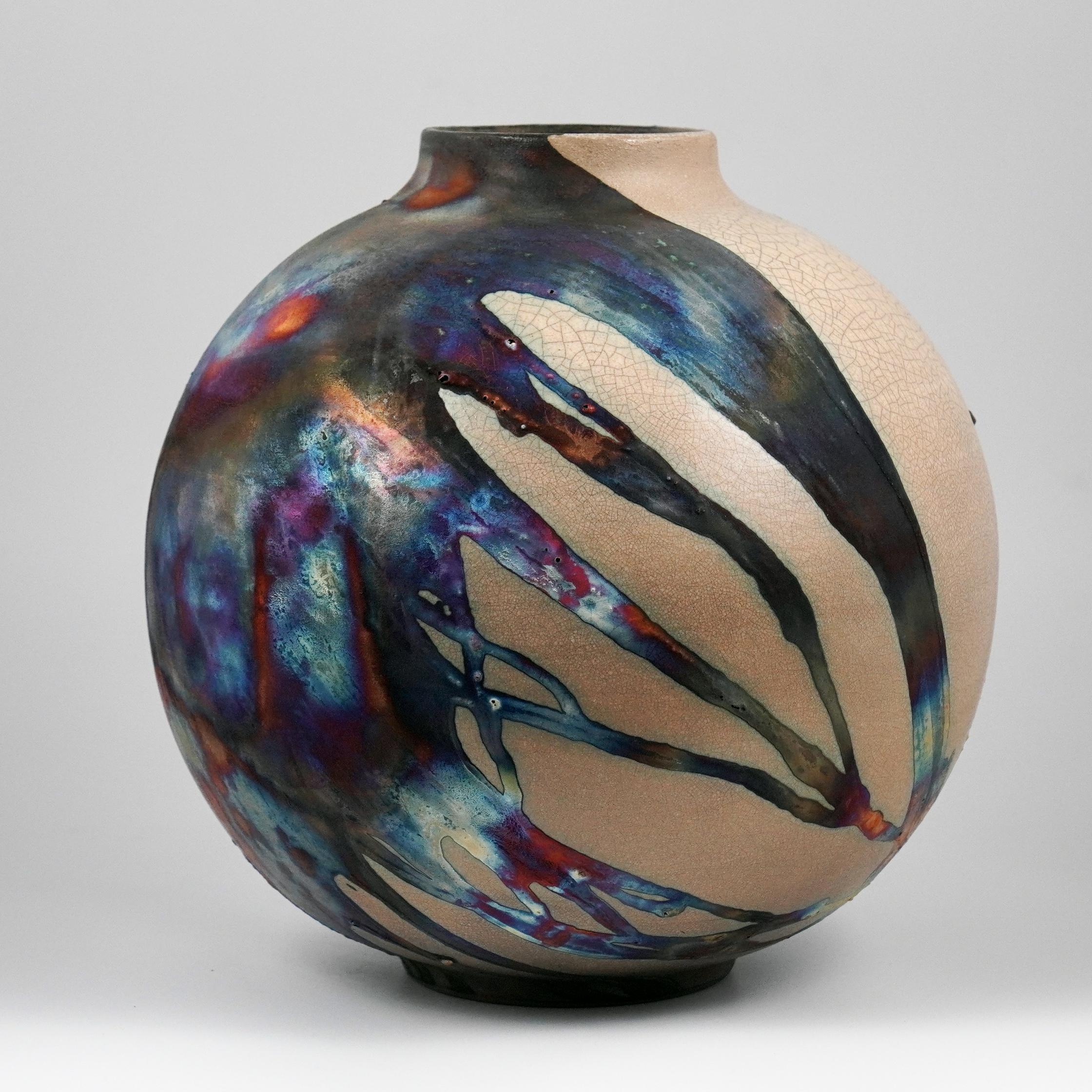 A mesmerizing sight to behold as soon as the rainbow-like patinas catch your eye. This Globe Vase is a round, capacious piece produced using the Raku technique, resulting in a beautiful unpredictable finish. This vase would be the perfect