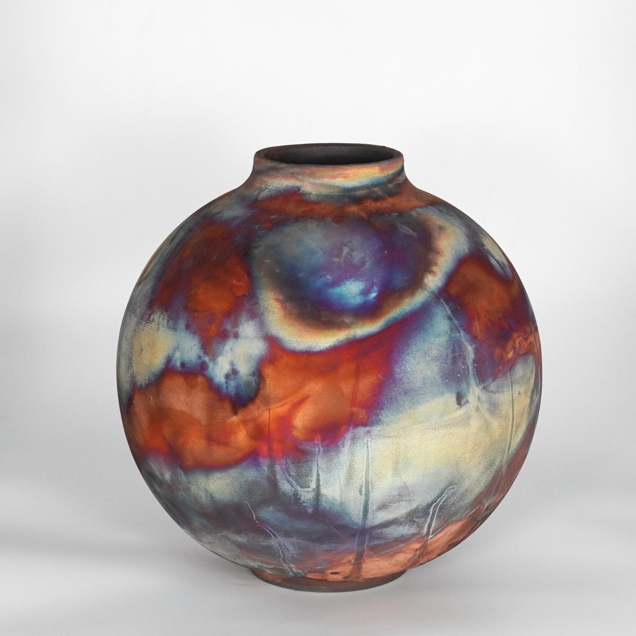 A mesmerizing sight to behold as soon as the rainbow-like patinas catch your eye. This Globe Vase is a round, capacious piece produced using the Raku technique, resulting in a beautiful unpredictable finish. This vase would be the perfect