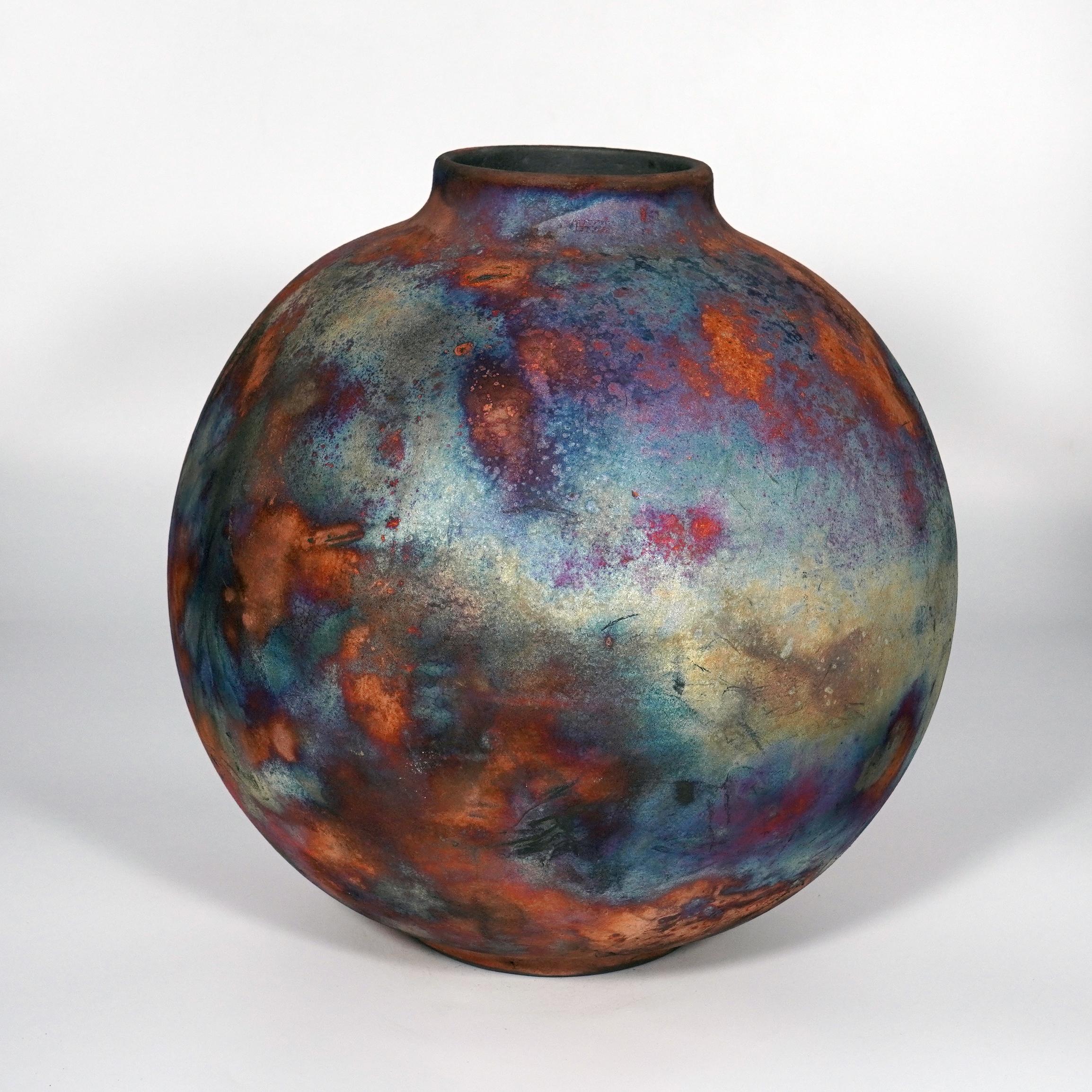 A mesmerizing sight to behold as soon as the rainbow-like patinas catch your eye. This Globe Vase is a round, capacious piece produced using the Raku technique, resulting in a beautiful unpredictable finish. This vase would be the perfect