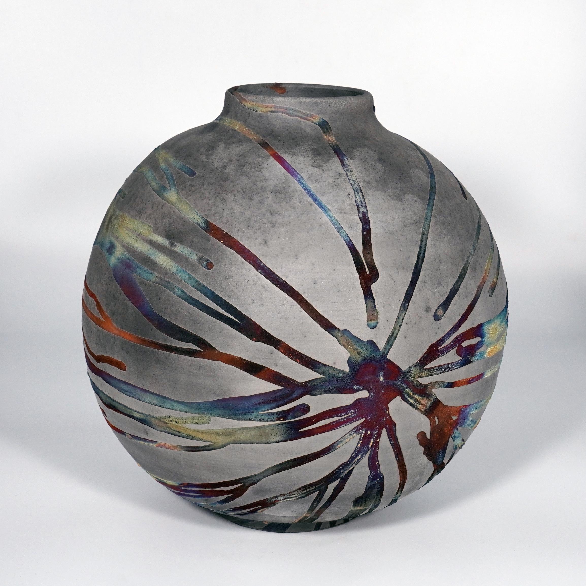 A mesmerizing sight to behold as soon as the rainbow-like patinas catch your eye. This Globe Vase is a round, capacious piece produced using the Raku technique, resulting in a beautiful unpredictable finish. This vase would be the perfect