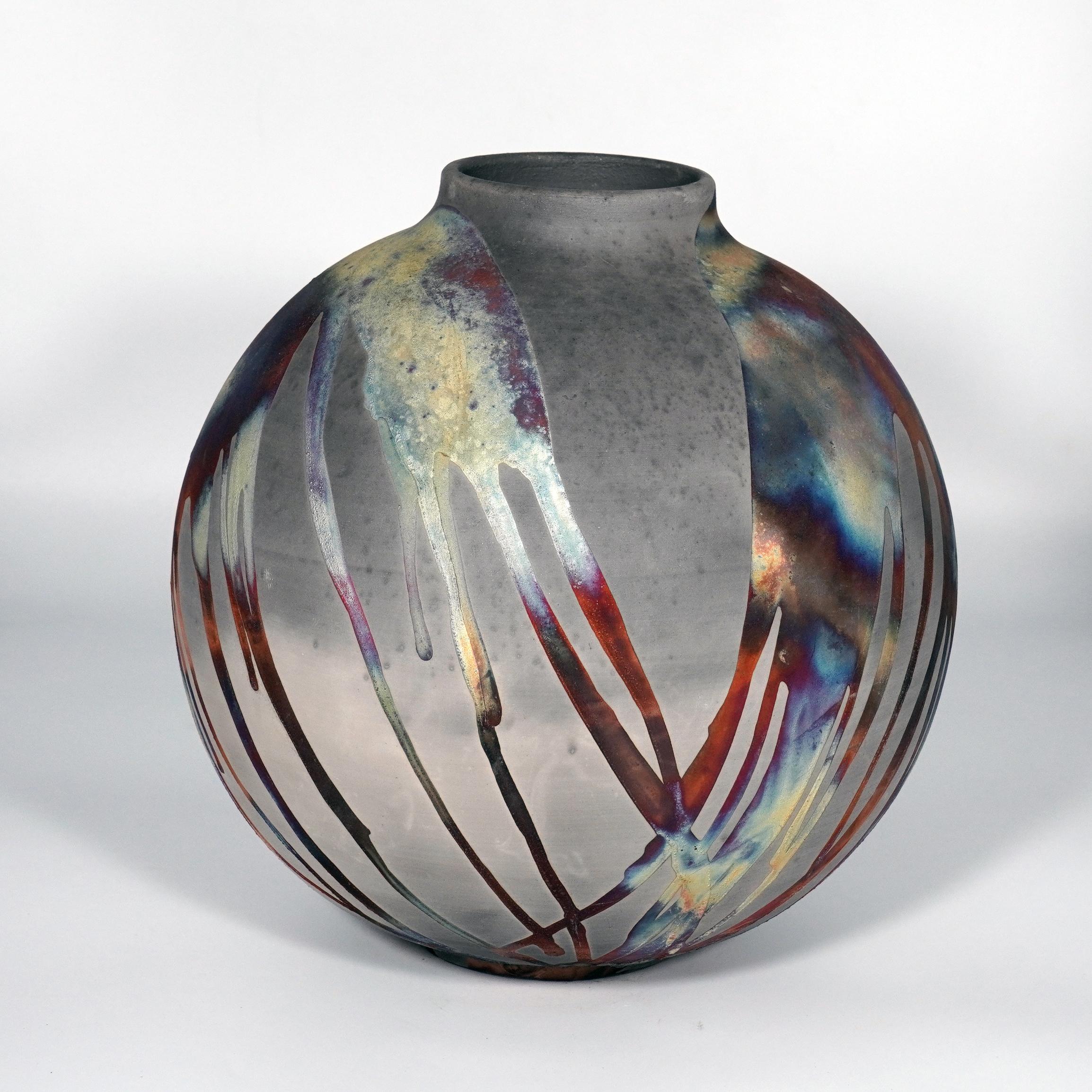 A mesmerizing sight to behold as soon as the rainbow-like patinas catch your eye. This Globe Vase is a round, capacious piece produced using the Raku technique, resulting in a beautiful unpredictable finish. This vase would be the perfect