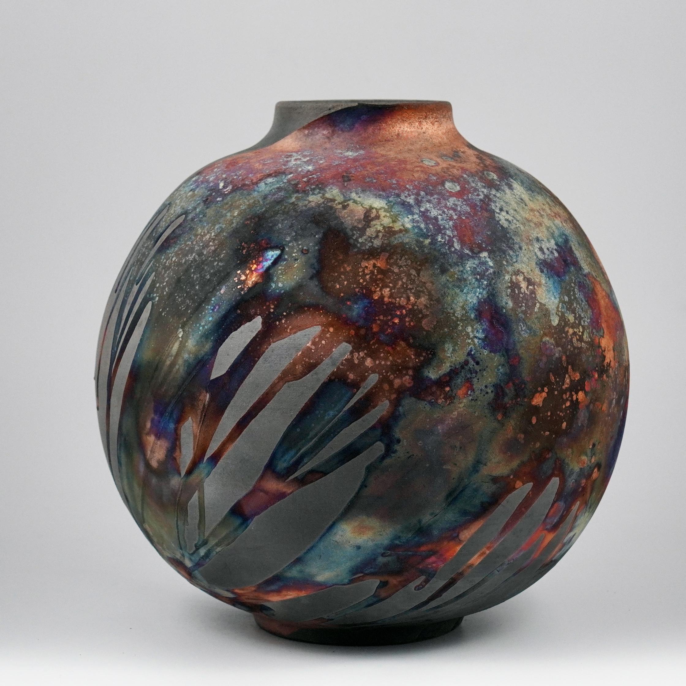A mesmerizing sight to behold as soon as the rainbow-like patinas catch your eye. This Globe Vase is a round, capacious piece produced using the Raku technique, resulting in a beautiful unpredictable finish. This vase would be the perfect
