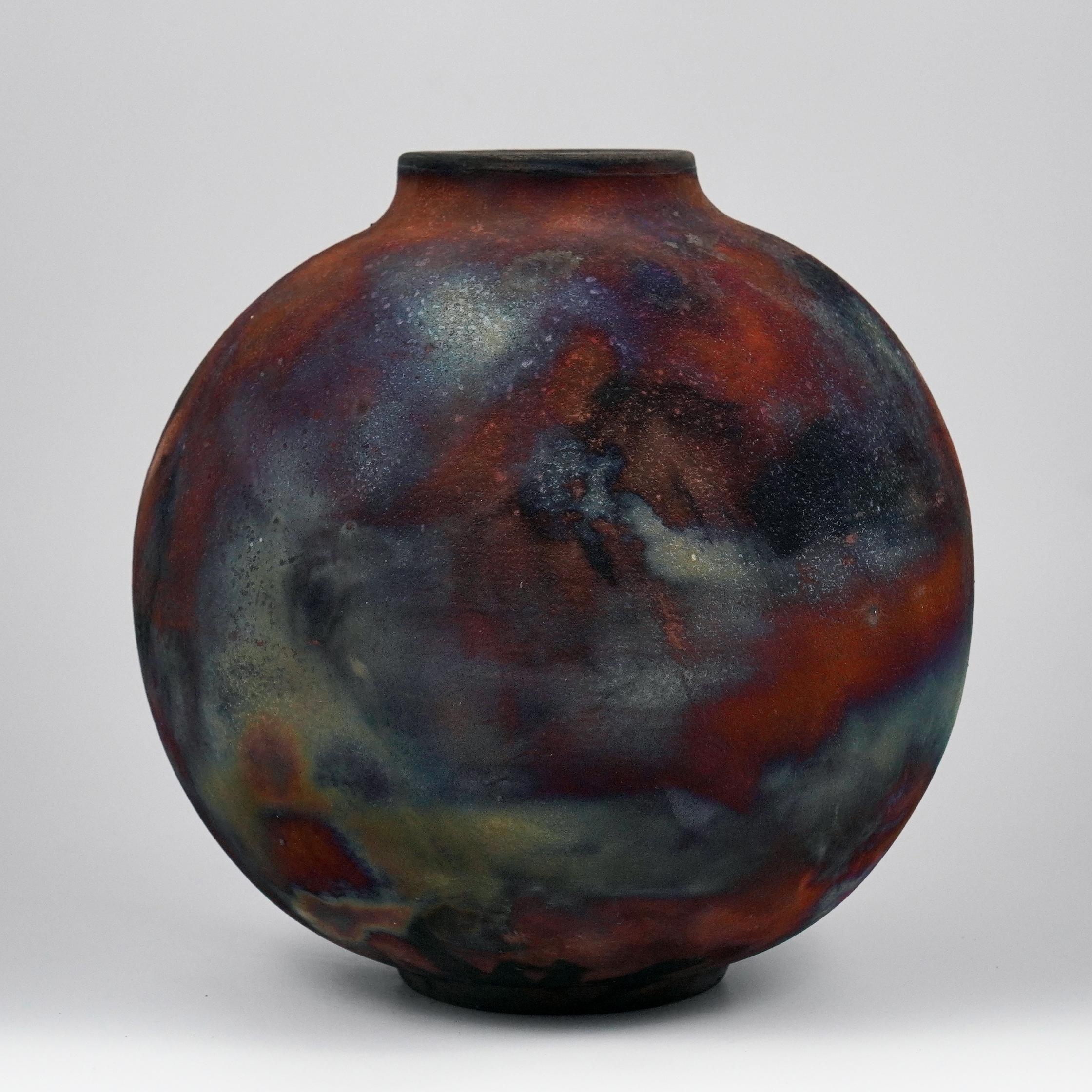 A mesmerizing sight to behold as soon as the rainbow-like patinas catch your eye. This Globe Vase is a round, capacious piece produced using the Raku technique, resulting in a beautiful unpredictable finish. This vase would be the perfect