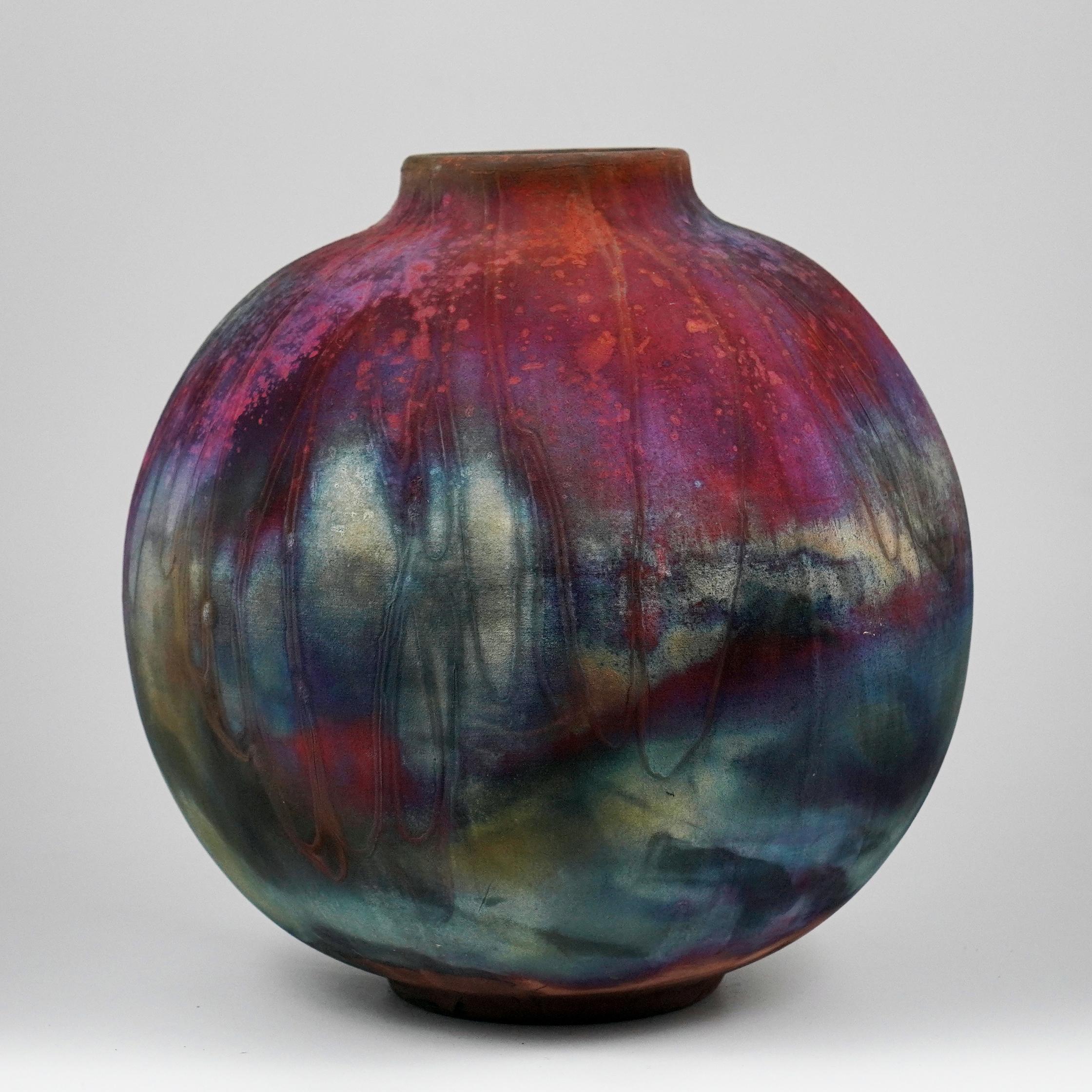 A mesmerizing sight to behold as soon as the rainbow-like patinas catch your eye. This Globe Vase is a round, capacious piece produced using the Raku technique, resulting in a beautiful unpredictable finish. This vase would be the perfect