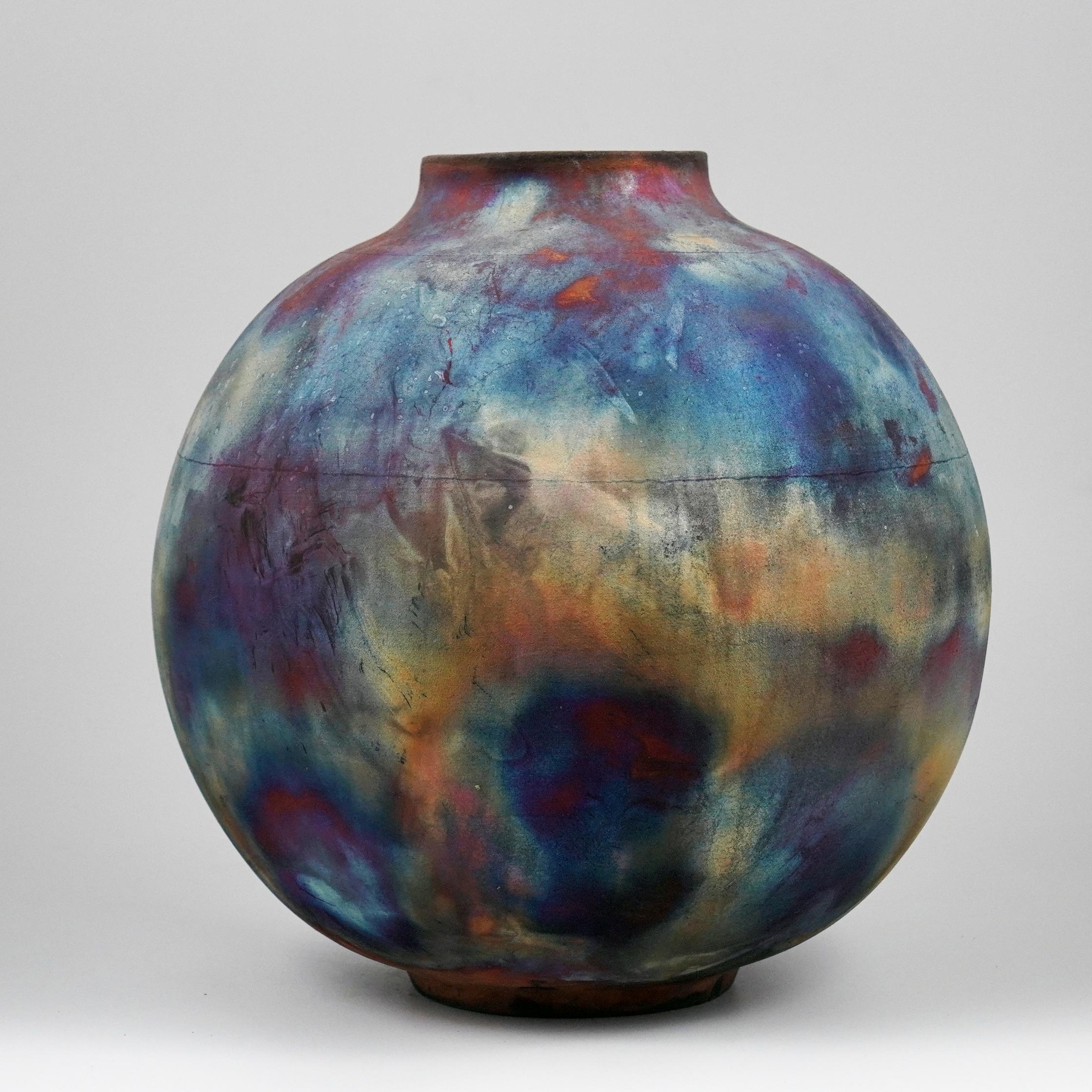 A mesmerizing sight to behold as soon as the rainbow-like patinas catch your eye. This Globe Vase is a round, capacious piece produced using the Raku technique, resulting in a beautiful unpredictable finish. This vase would be the perfect
