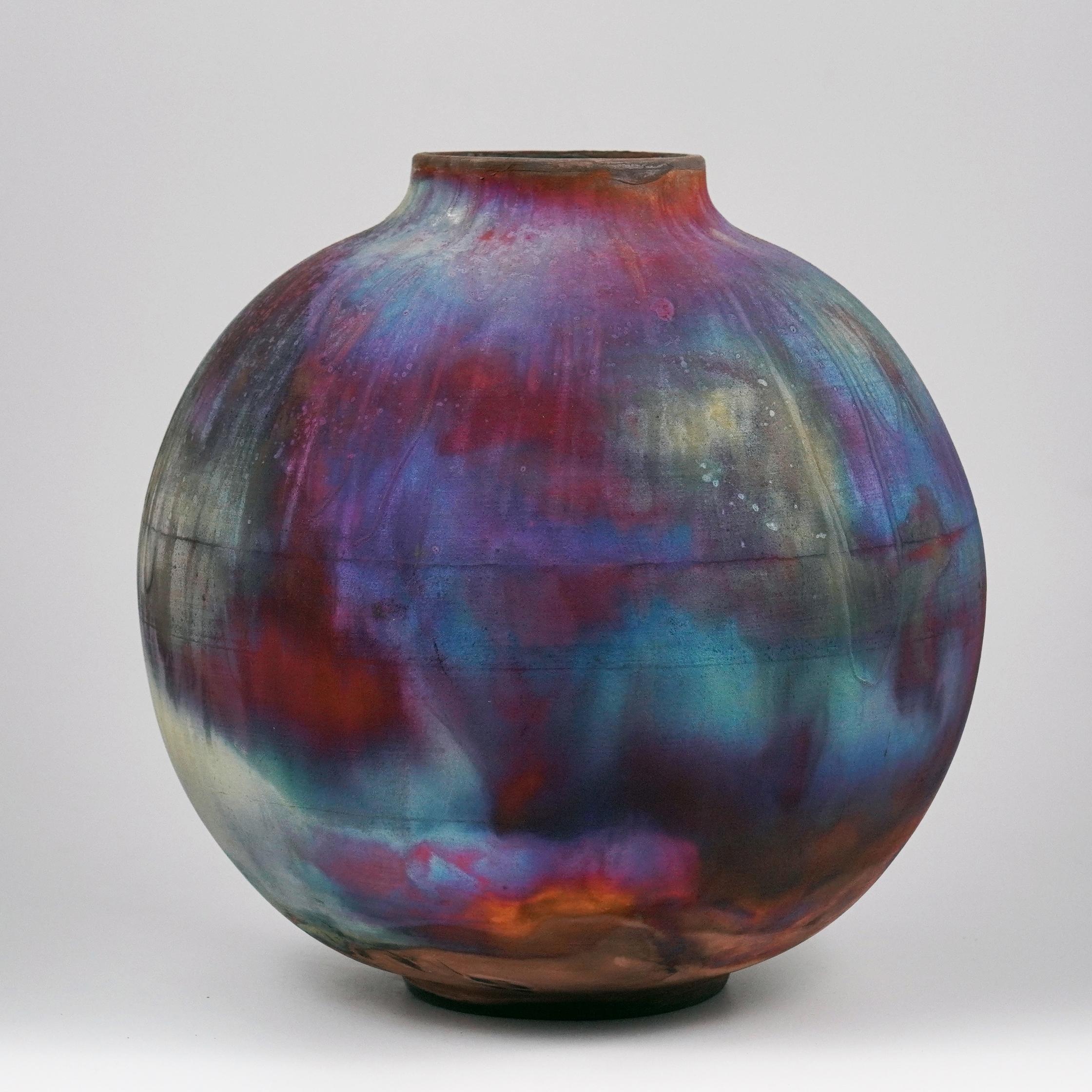 A mesmerizing sight to behold as soon as the rainbow-like patinas catch your eye. This Globe Vase is a round, capacious piece produced using the Raku technique, resulting in a beautiful unpredictable finish. This vase would be the perfect