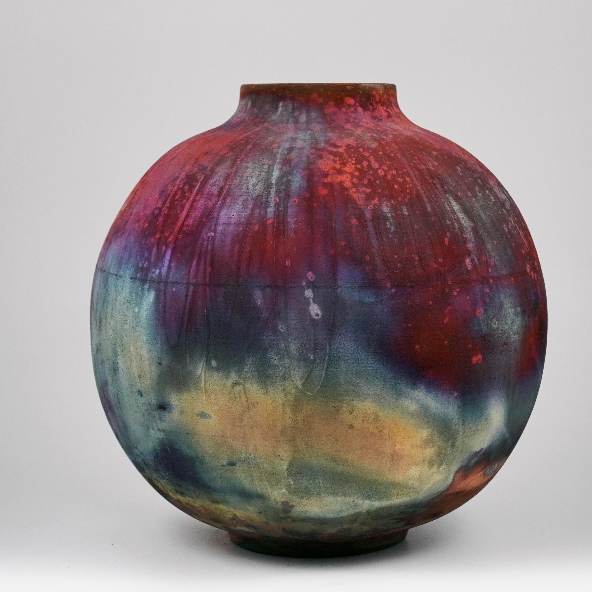 A mesmerizing sight to behold as soon as the rainbow-like patinas catch your eye. This Globe Vase is a round, capacious piece produced using the Raku technique, resulting in a beautiful unpredictable finish. This vase would be the perfect