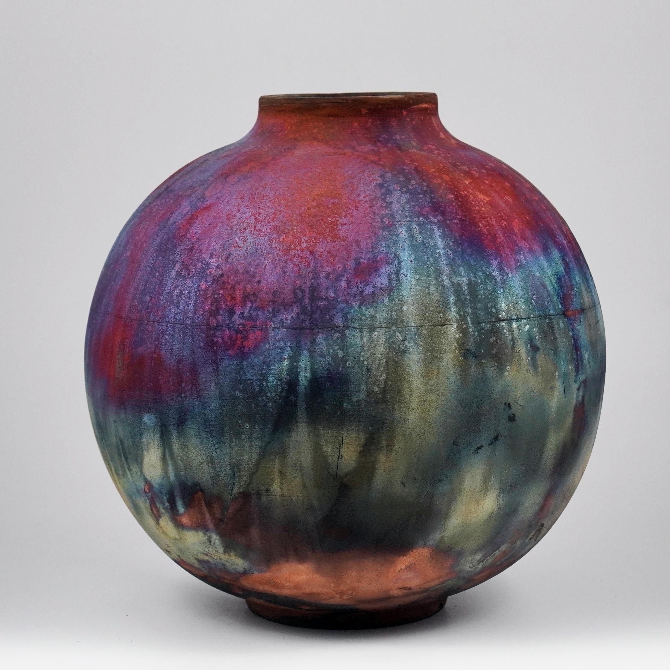 A mesmerizing sight to behold as soon as the rainbow-like patinas catch your eye. This Globe Vase is a round, capacious piece produced using the Raku technique, resulting in a beautiful unpredictable finish. This vase would be the perfect