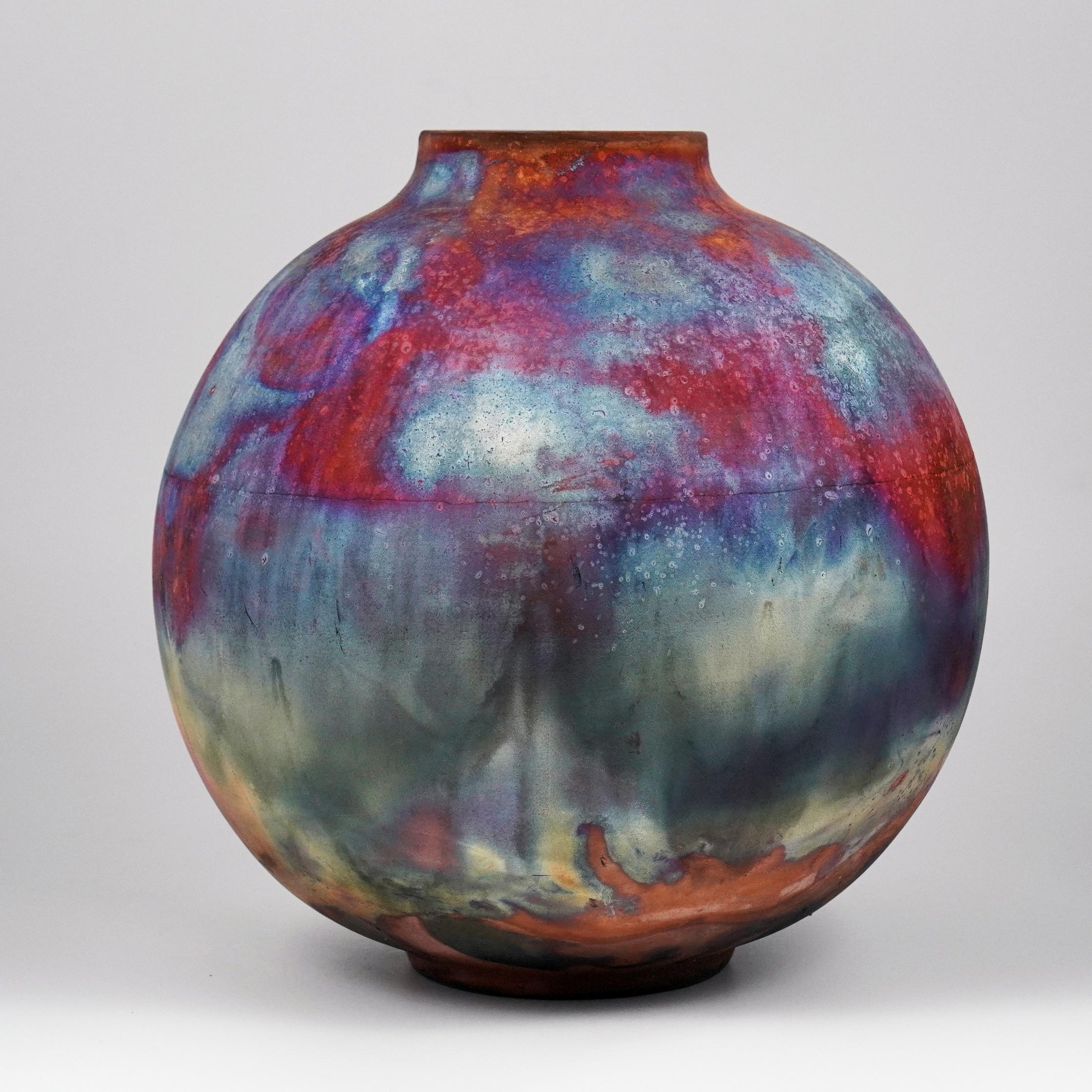 A mesmerizing sight to behold as soon as the rainbow-like patinas catch your eye. This Globe Vase is a round, capacious piece produced using the Raku technique, resulting in a beautiful unpredictable finish. This vase would be the perfect