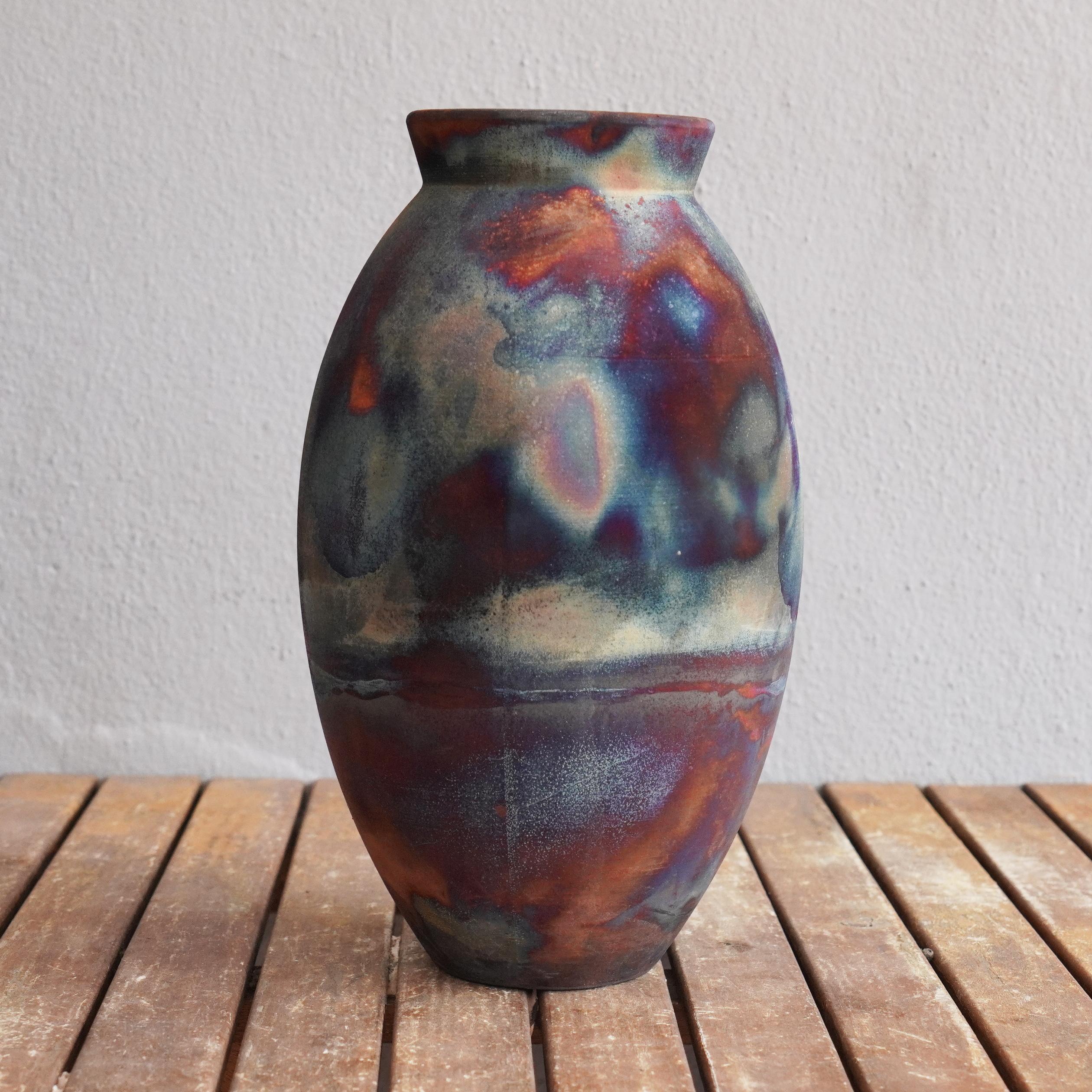 A mesmerizing sight to behold as soon as the rainbow-like patinas catch your eye. The Oval Vase is a tall, teardrop-shaped design best for adding a touch of elegance and intrigue to an interior space. Made using the Raku technique, it easily becomes
