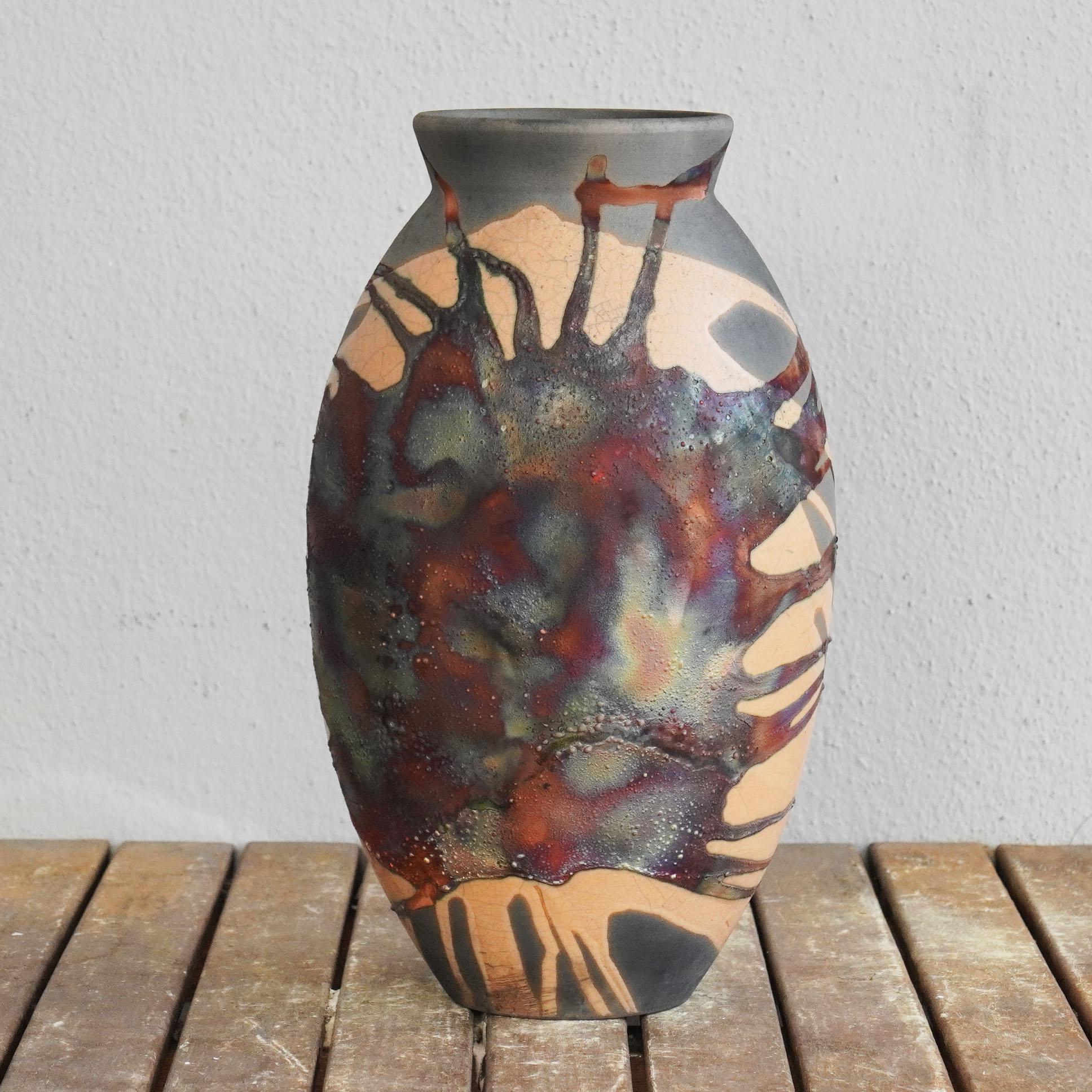 A mesmerizing sight to behold as soon as the rainbow-like patinas catch your eye. The Oval Vase is a tall, teardrop-shaped design best for adding a touch of elegance and intrigue to an interior space. Made using the Raku technique, it easily becomes