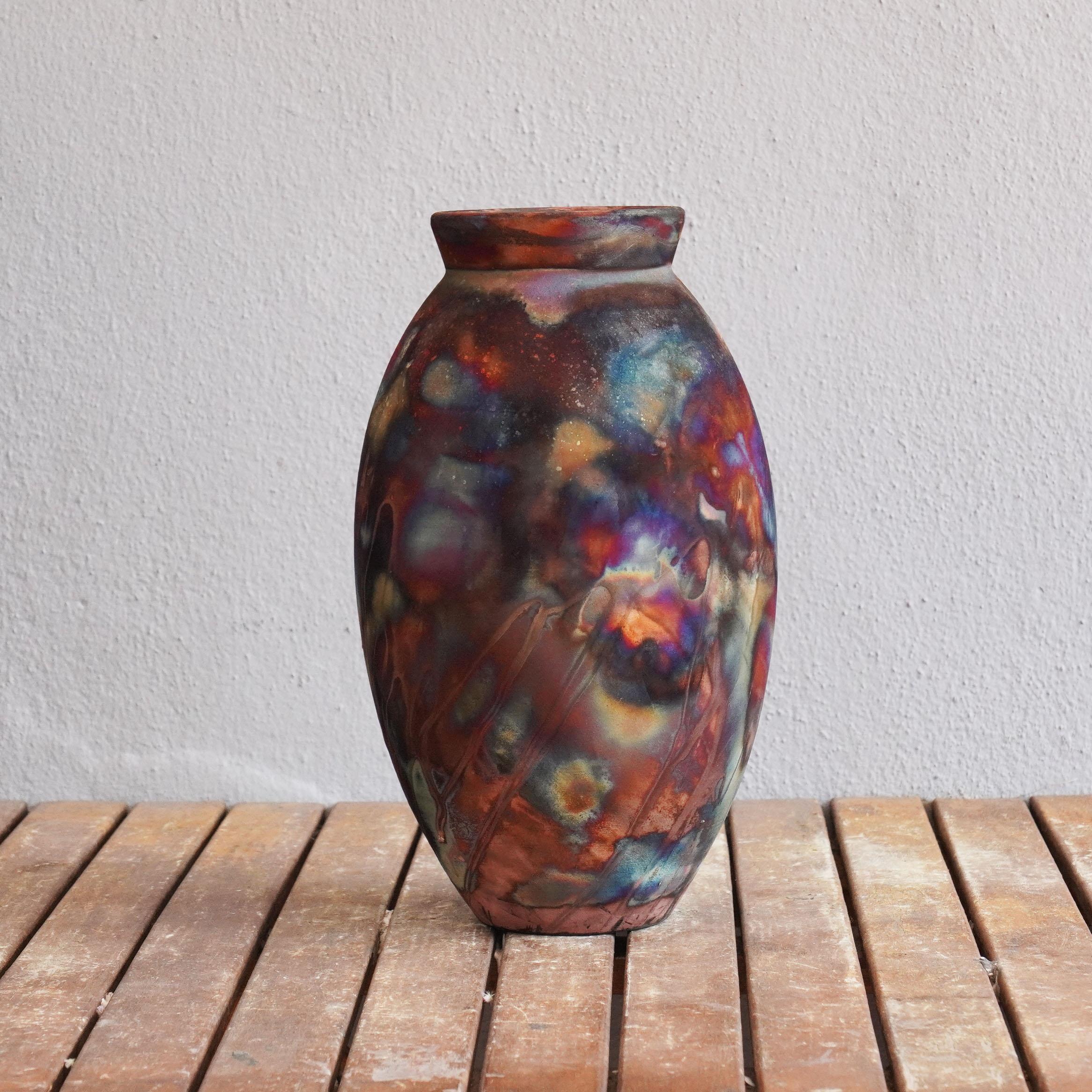 A mesmerizing sight to behold as soon as the rainbow-like patinas catch your eye. The Oval Vase is a tall, teardrop-shaped design best for adding a touch of elegance and intrigue to an interior space. Made using the Raku technique, it easily becomes