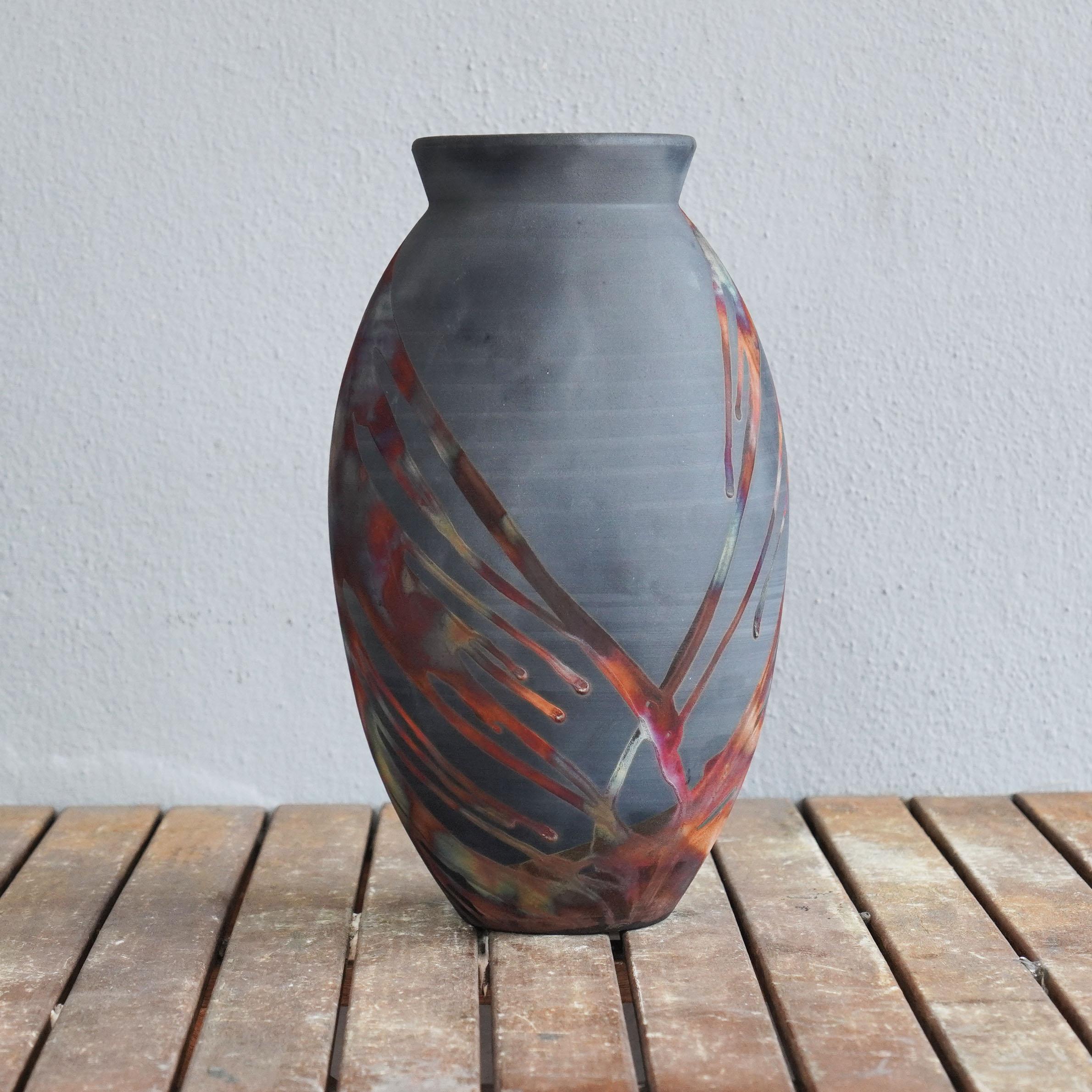 A mesmerizing sight to behold as soon as the rainbow-like patinas catch your eye. The Oval Vase is a tall, teardrop-shaped design best for adding a touch of elegance and intrigue to an interior space. Made using the Raku technique, it easily becomes