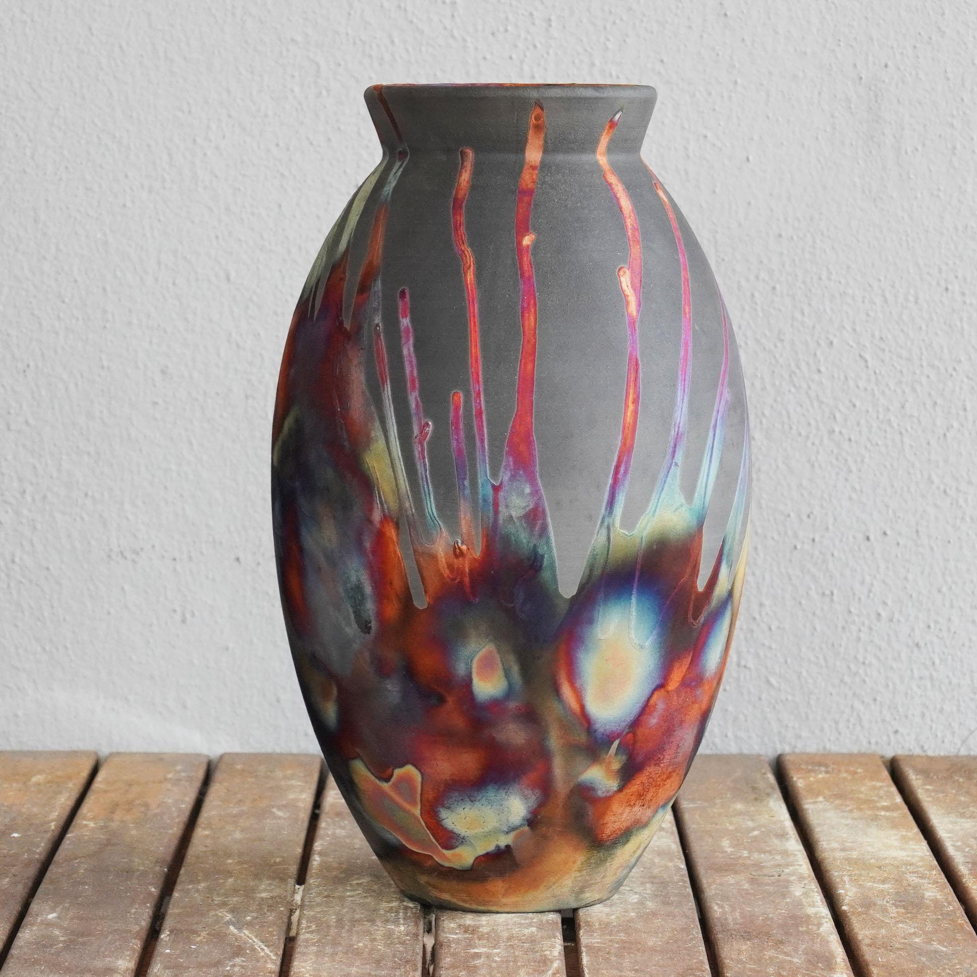 A mesmerizing sight to behold as soon as the rainbow-like patinas catch your eye. The Oval Vase is a tall, teardrop-shaped design best for adding a touch of elegance and intrigue to an interior space. Made using the Raku technique, it easily becomes