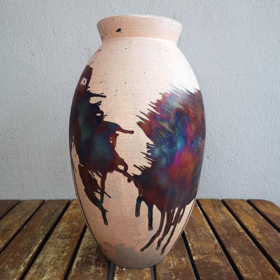 A mesmerizing sight to behold as soon as the rainbow-like patinas catch your eye. The Oval Vase is a tall, teardrop-shaped design best for adding a touch of elegance and intrigue to an interior space. Made using the Raku technique, it easily becomes