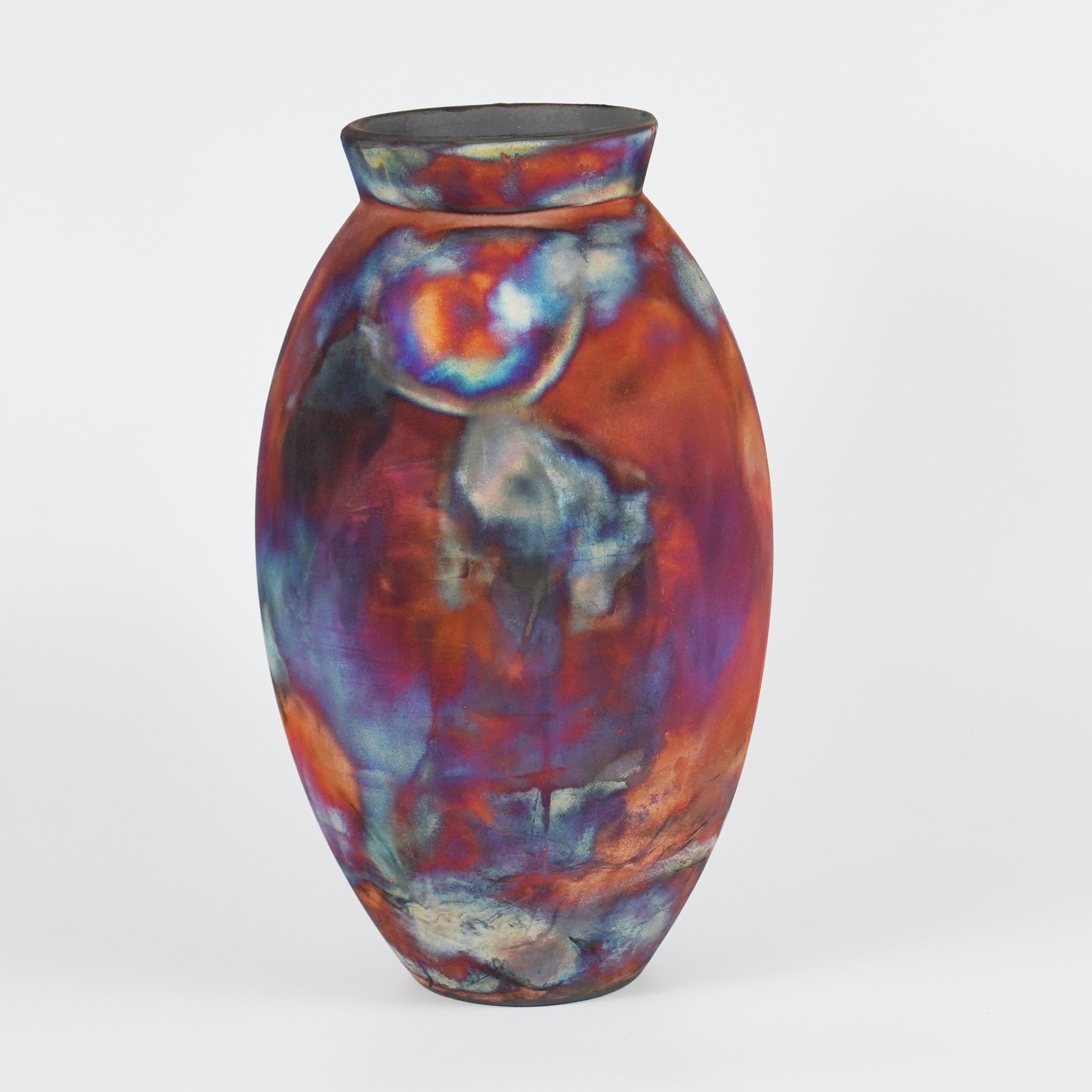 Ein faszinierender Anblick, sobald die regenbogenartigen Patinas ins Auge fallen. Die ovale Vase ist ein hohes, tropfenförmiges Design, das einen Hauch von Eleganz und Faszination in einen Innenraum bringt. Mit der Raku-Technik hergestellt, wird sie