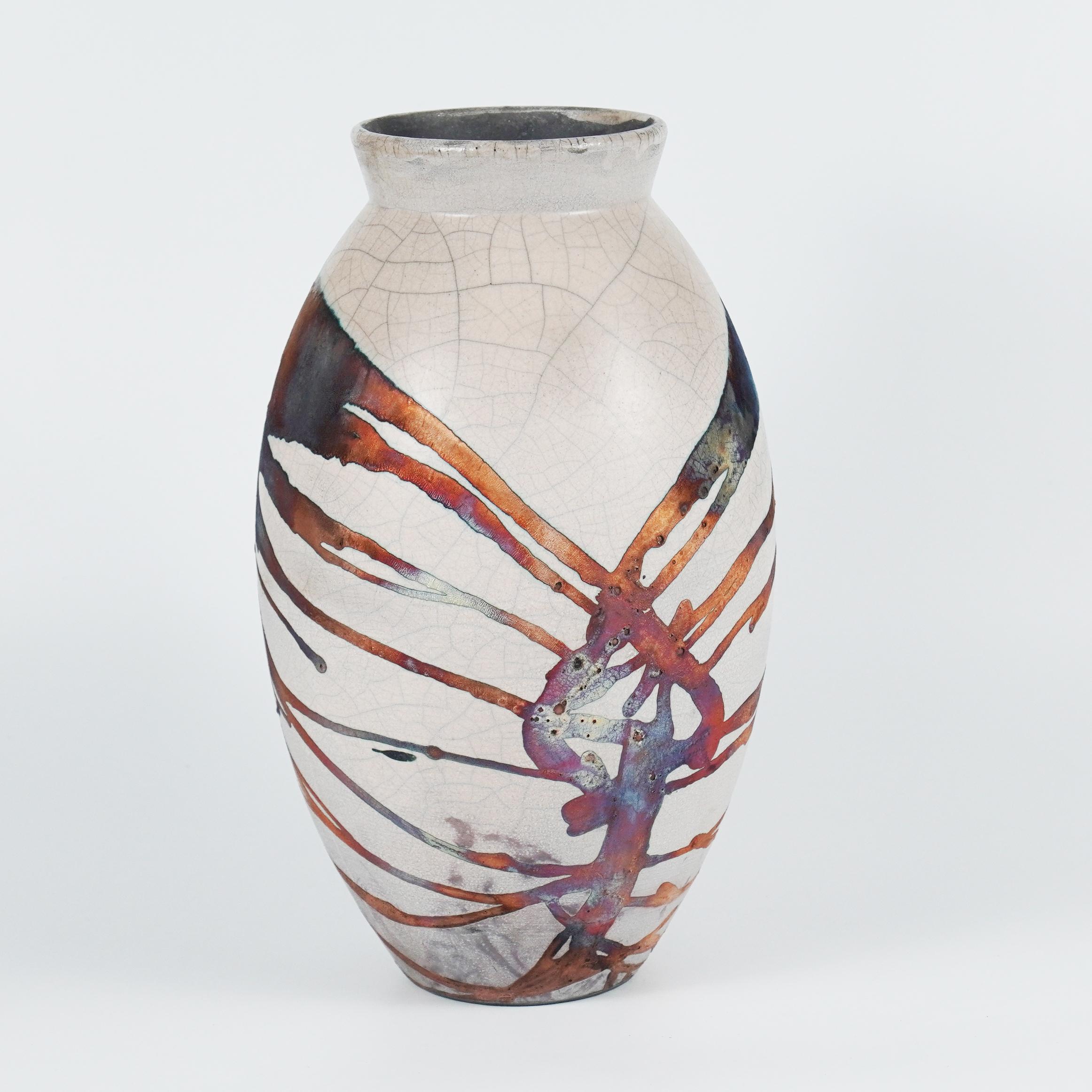 Ein faszinierender Anblick, sobald die regenbogenartigen Patinas ins Auge fallen. Die ovale Vase ist ein hohes, tropfenförmiges Design, das einen Hauch von Eleganz und Faszination in einen Innenraum bringt. Mit der Raku-Technik hergestellt, wird sie