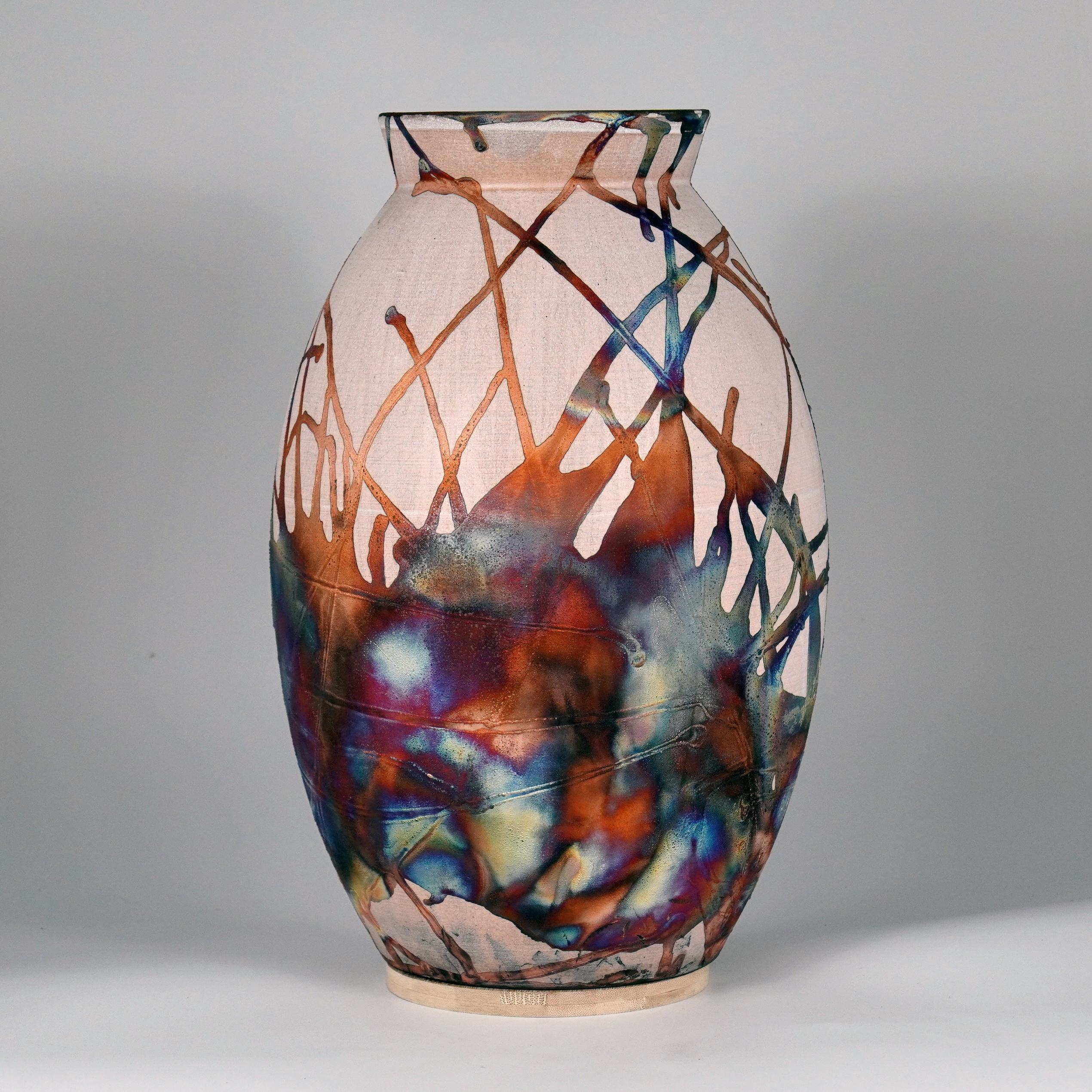 A mesmerizing sight to behold as soon as the rainbow-like patinas catch your eye. The Oval XL Vase is a tall, teardrop-shaped design best for adding a touch of elegance and intrigue to an interior space. Made using the Raku technique, it easily