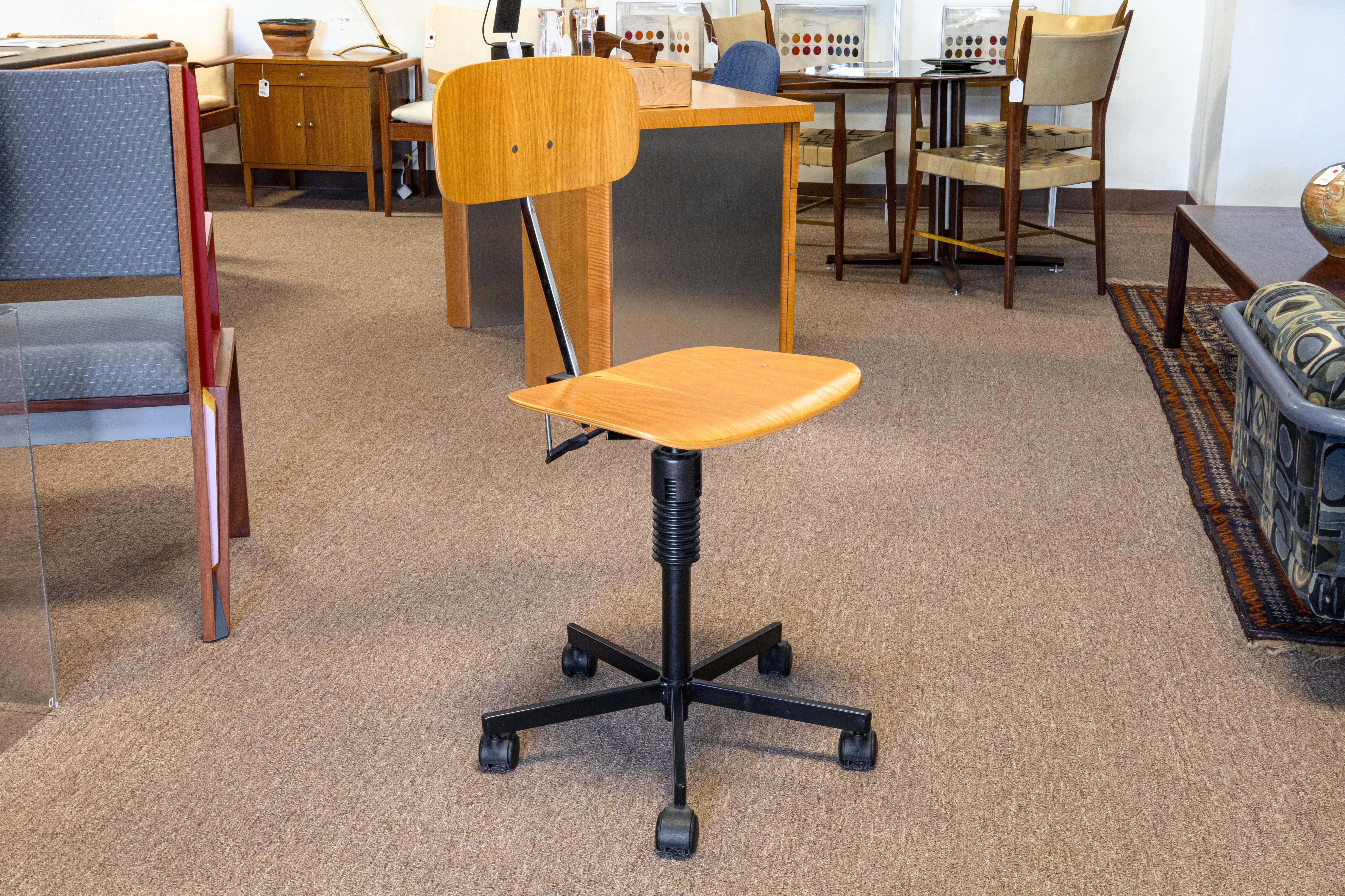 A Rabami Stole task desk chair. This lovely little desk chair features a classic mid century modern design. Made in Denmark, this chair features a wood seat and back, a metal and plastic frame, a swiveling and adjustable seat, an adjustable