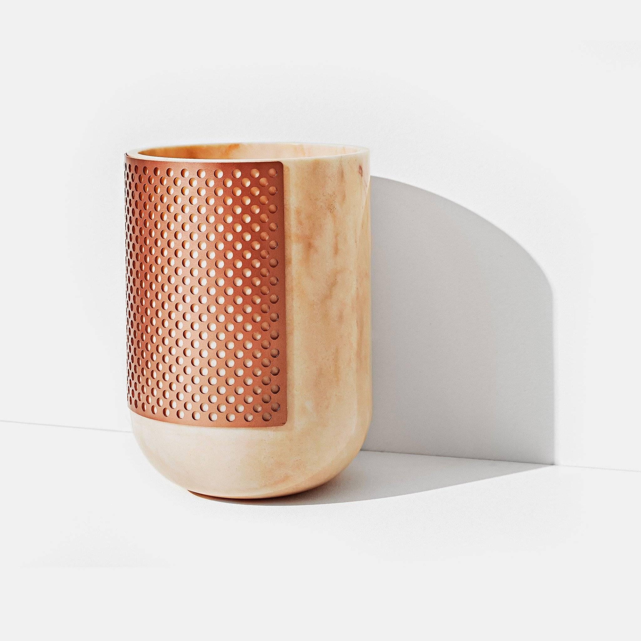 Rabbet is a vase in solid marble with soft and linear shapes partially covered by the perforated copper coloured metal sheath.

Materials: 
Bianco Lasa Covelano marble and copper metal grid

or 

Rosa Portogallo marble and copper coloured metal