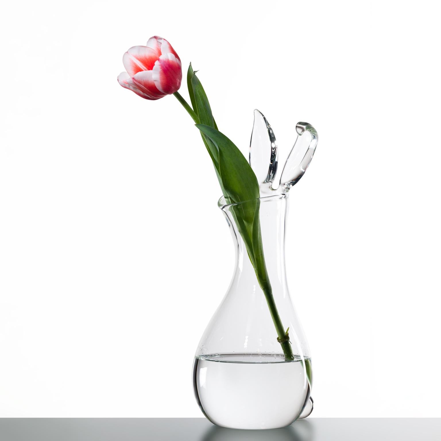 Introducing the whimsical Rabbit Vase, a charming hand-blown glass creation by the talented Simone Crestani. This delicate decanter, crafted entirely in transparent glass, features a classic silhouette with a playful twist. The design leans slightly