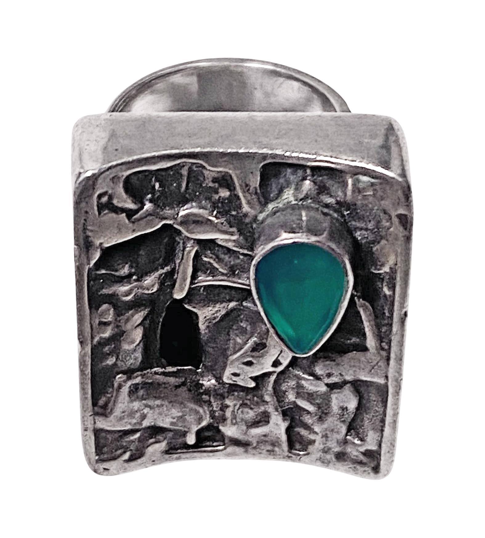Rachel Gera abstract brutalist Modernist Sterling Ring, Israel, C.1975. Rectangular oxidised and high points polished abstract form accented with bezel set pear facetted green paste stone. Signed on underside Gera in English and Hebrew. Rachel Gera,