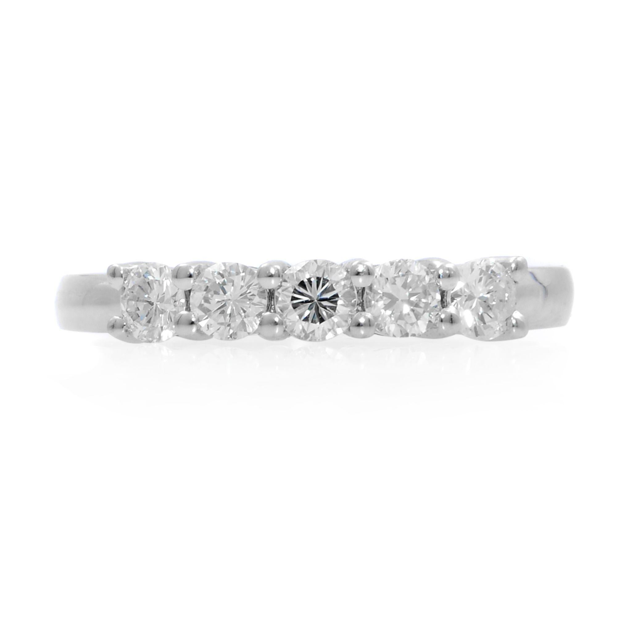 This ring if crafted in 14k white gold. Semi eternity diamond wedding band features five round diamonds across a glistening metal band. The diamonds shine brightly like stars in the night sky and are held in a prong setting for maximum brilliance.