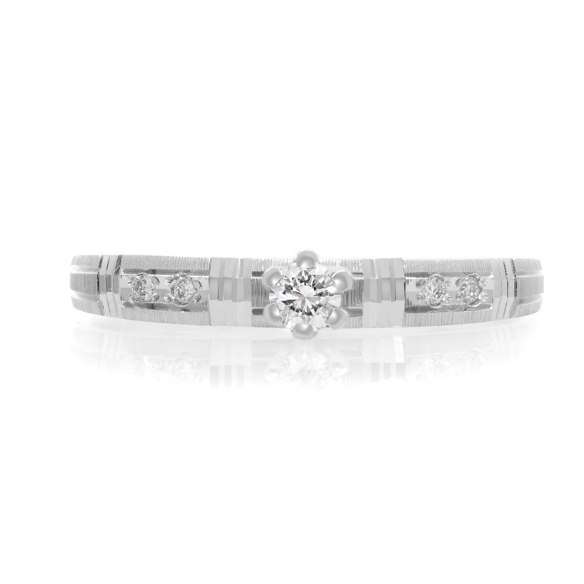 This simple engagement ring features a round cut 0.10 carat diamond solitaire, showing brilliance and a unique sophistication. The shank is embellished with channel-set tiny diamond accents to add more beauty. It is crafted in 14k white gold. Total