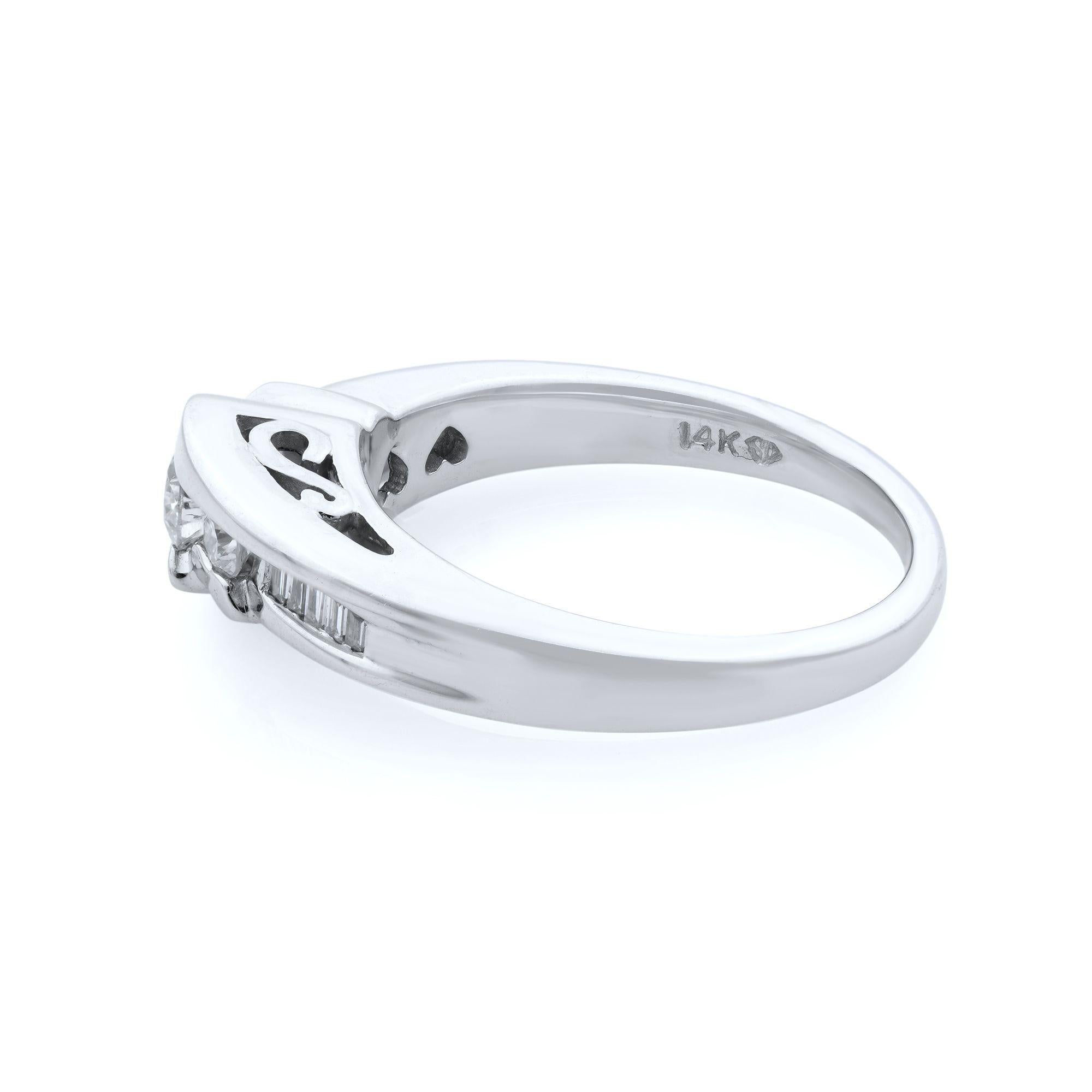 This engagement ring features a low, half-bezel setting with a flared band. Round cut center stone and two round cuts on each side, shank channel set with tiny baguettes. The ring has a spectacular little engraving on the sides of the piece. Total