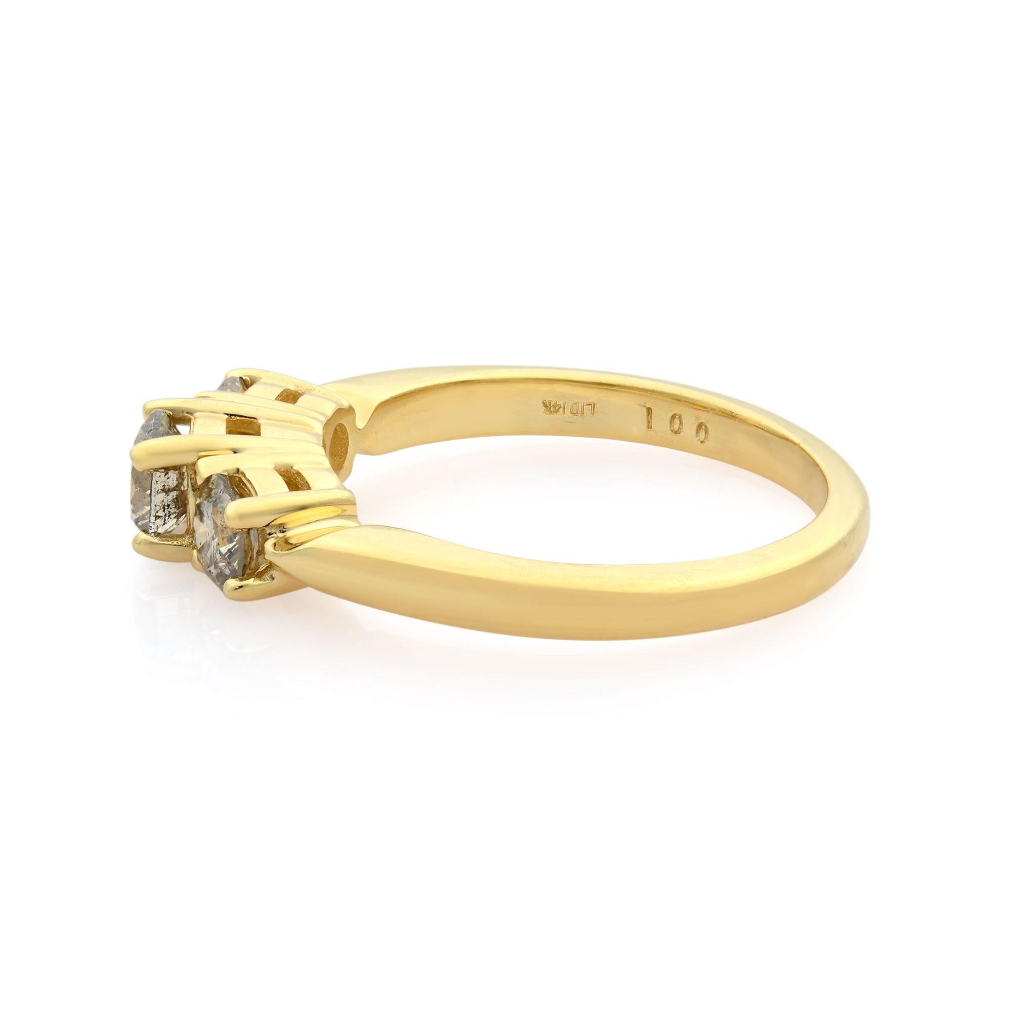 Dieser Ring mit drei Steinen besteht aus einem runden Diamanten in Zackenfassung in der Mitte, der von kleineren Diamanten flankiert wird. Die Fassung verleiht diesem Verlobungsring aus 14 Karat Gelbgold eine schöne Seitenansicht. Karatgewicht