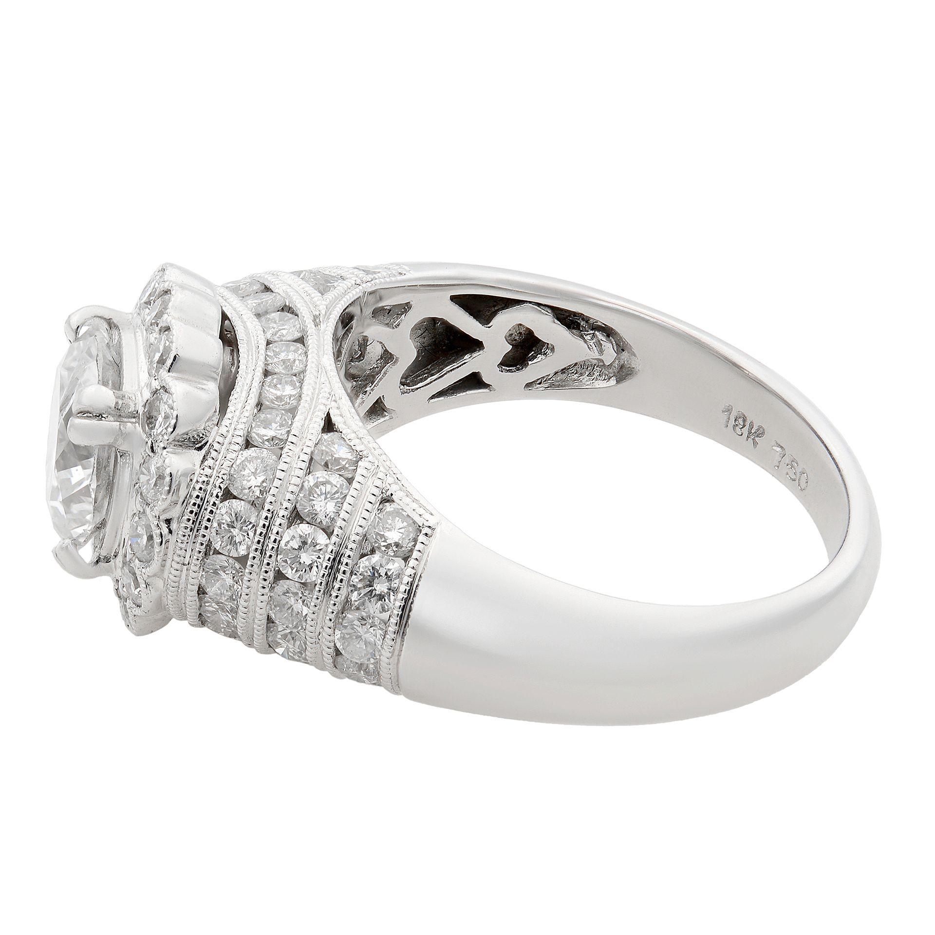 This gorgeous engagement ring is set with 1.26ct round cut center stone with a halo and a channel set diamonds around on a thick shank. Very elegant looking ring and beautifully shining stones. Total carat weight 2.73ct. Diamonds are aprox. VS2