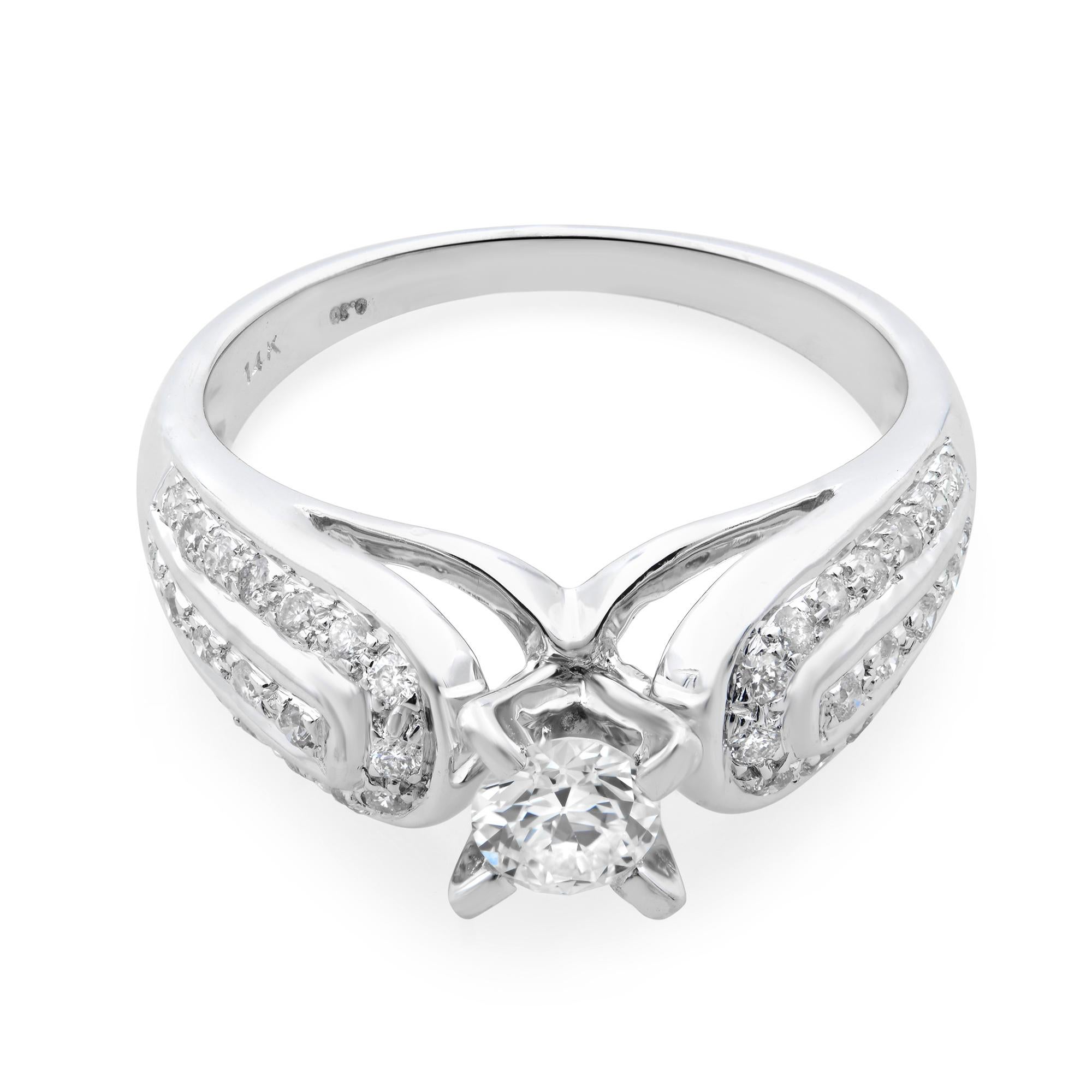 Precioso anillo de compromiso de diamantes sin estrenar realizado en oro blanco de 14 quilates. Este anillo presenta un diamante de talla redonda con color G y claridad VS2. La piedra central está engastada con 4 puntas y pequeños diamantes