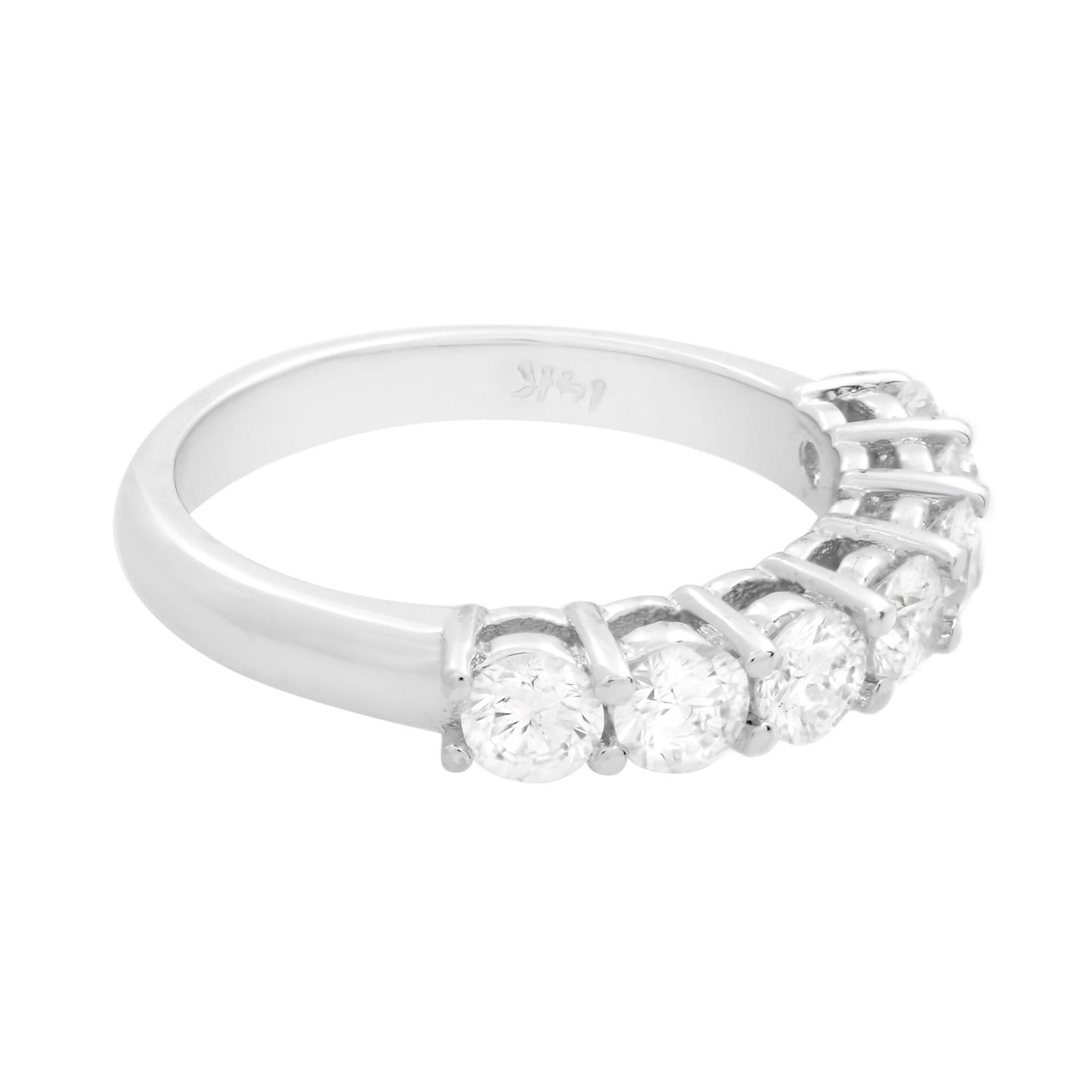 This ring is crafted in 14k white gold. Semi eternity diamond wedding band that features seven round diamonds across a glistening metal band. The diamonds shine brightly like stars in the night sky and are held in a prong setting for maximum