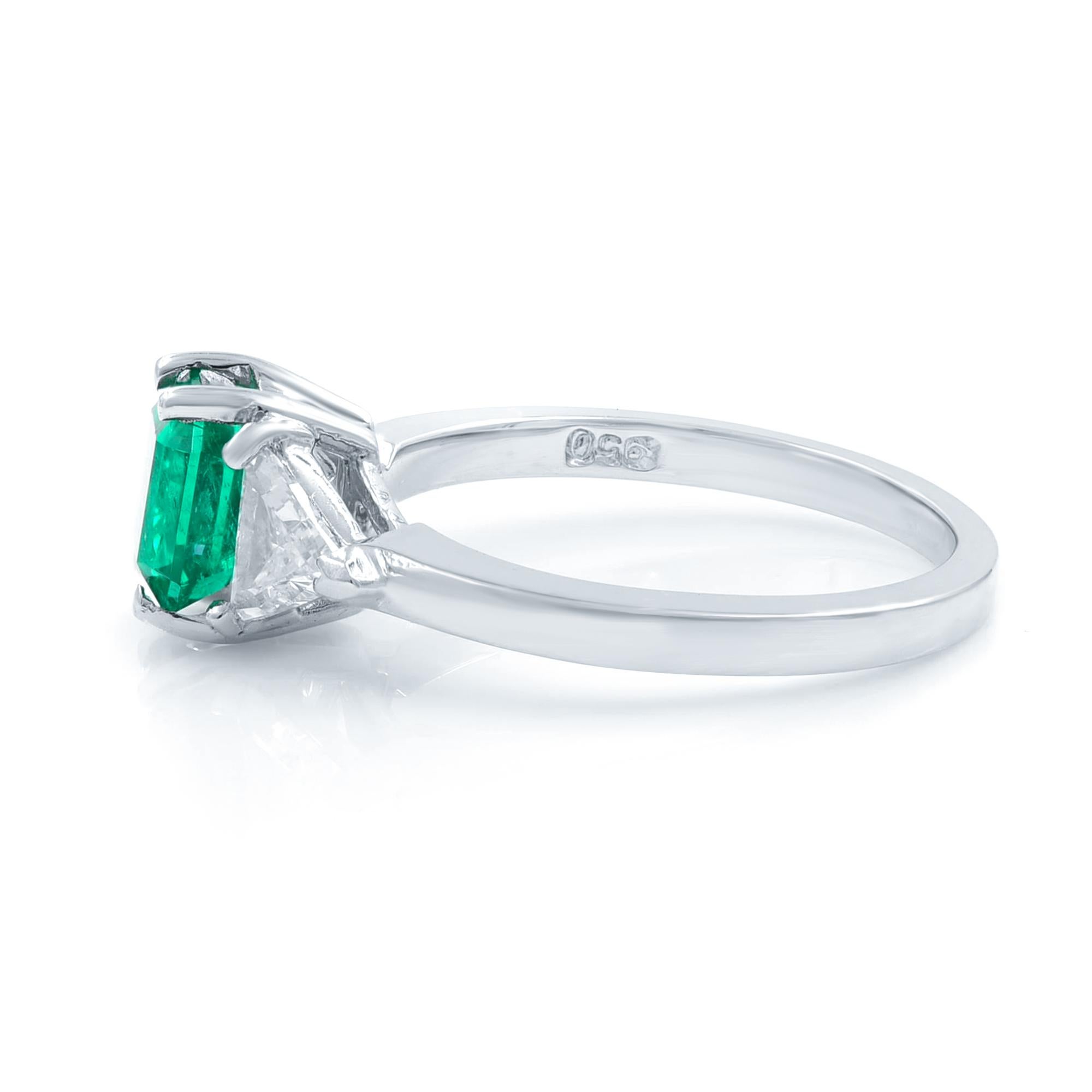 A bright vibrant crystalline green Colombian emerald with soft shouldered square emerald-cut, radiates between sparkling white trillion-cut diamonds in this classic estate jewel rendered in lustrous platinum. Timeless. Center Emerald: 1.80cts. Side