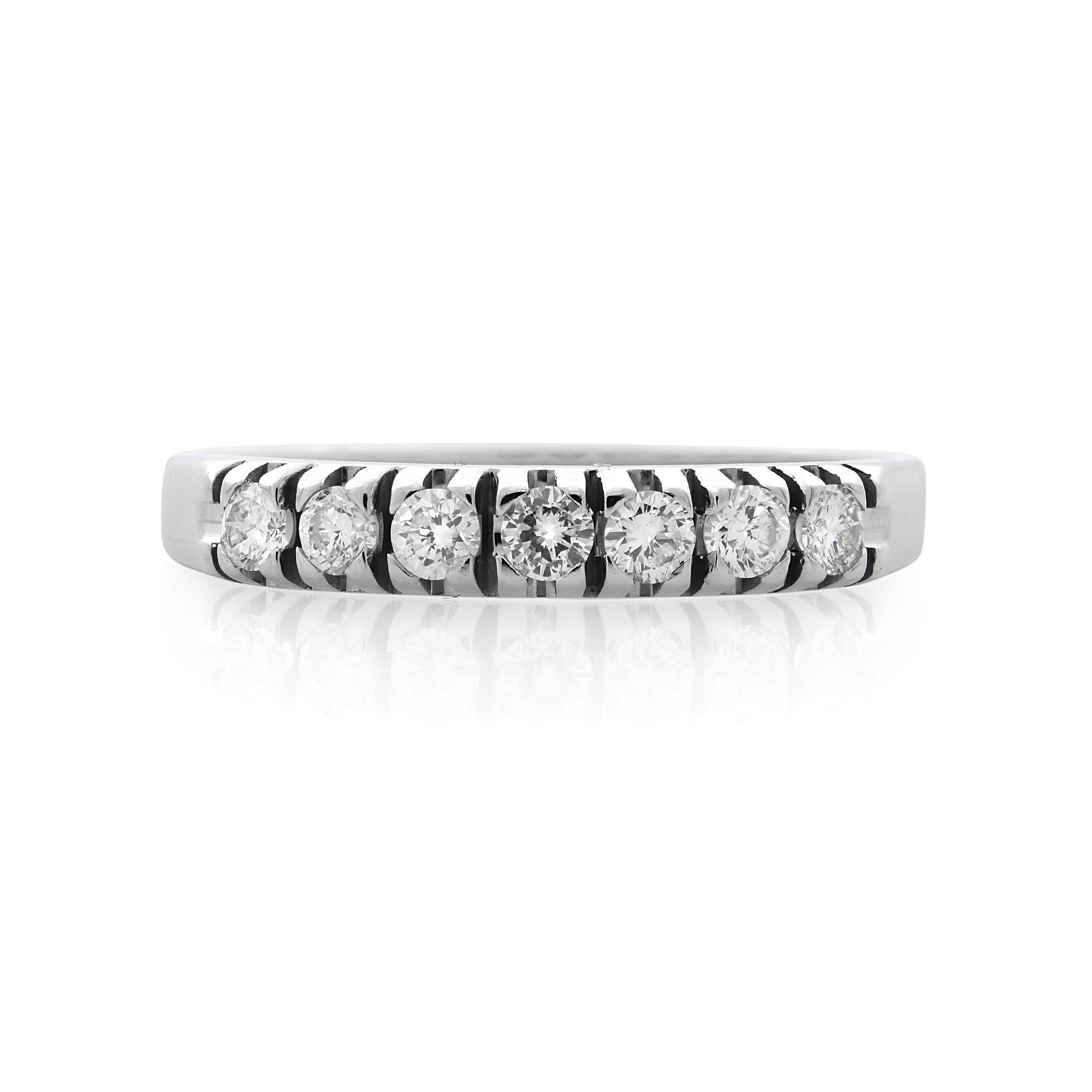 Delicately crafted, small pave diamond wedding band. Features 7 diamonds along the top of the ring to create a fine line of brilliance. Crafted in 14k white gold. Total carat weight of the diamonds 0.21 cttw. The ring width 3.00 mm., size: 7.5.