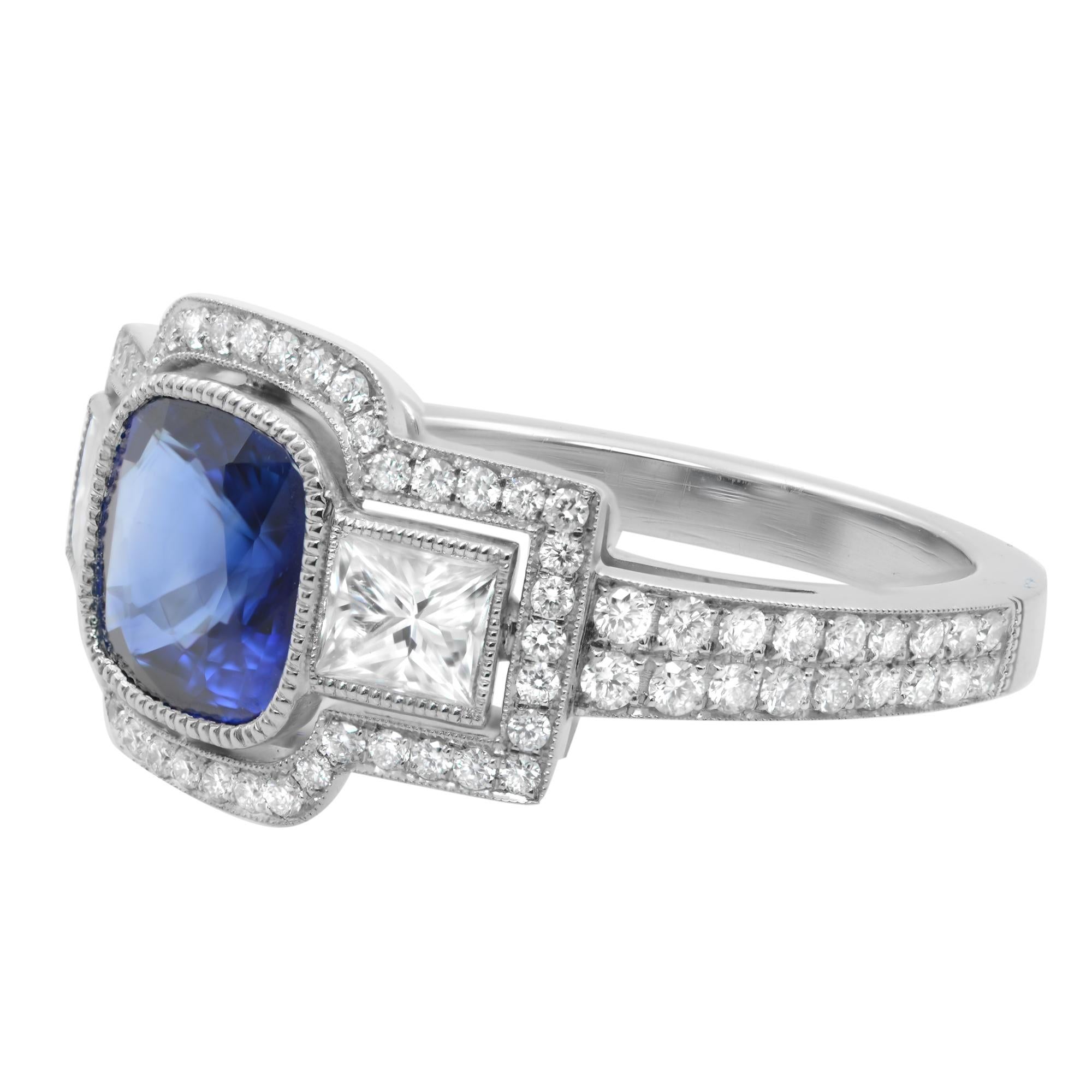 A darling and delicate, traditional style, newly made estate-style Blue Sapphire engagement ring crafted in platinum. The ring centers one bright pure Blue cushion cut Sapphire framed by the high polished bezel and flanked by a princess and round