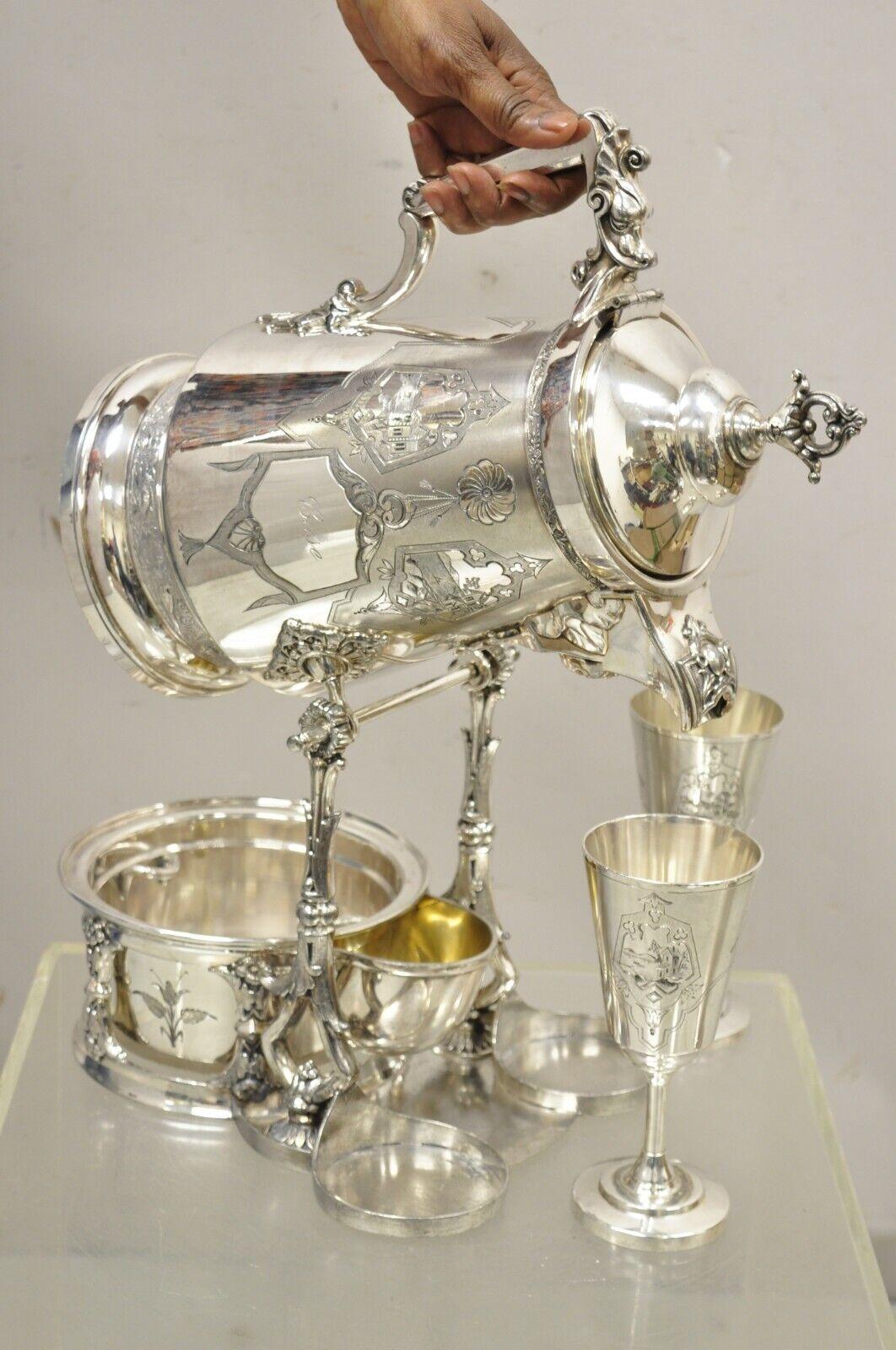 Racine Silverplated Victorian Tilting Lemonade Water Pitcher on Stand w/ Goblets. Item features stunning ornate figural details, Egyptian Revivial Face to spout of pitcher, dragon to handle, engraved 