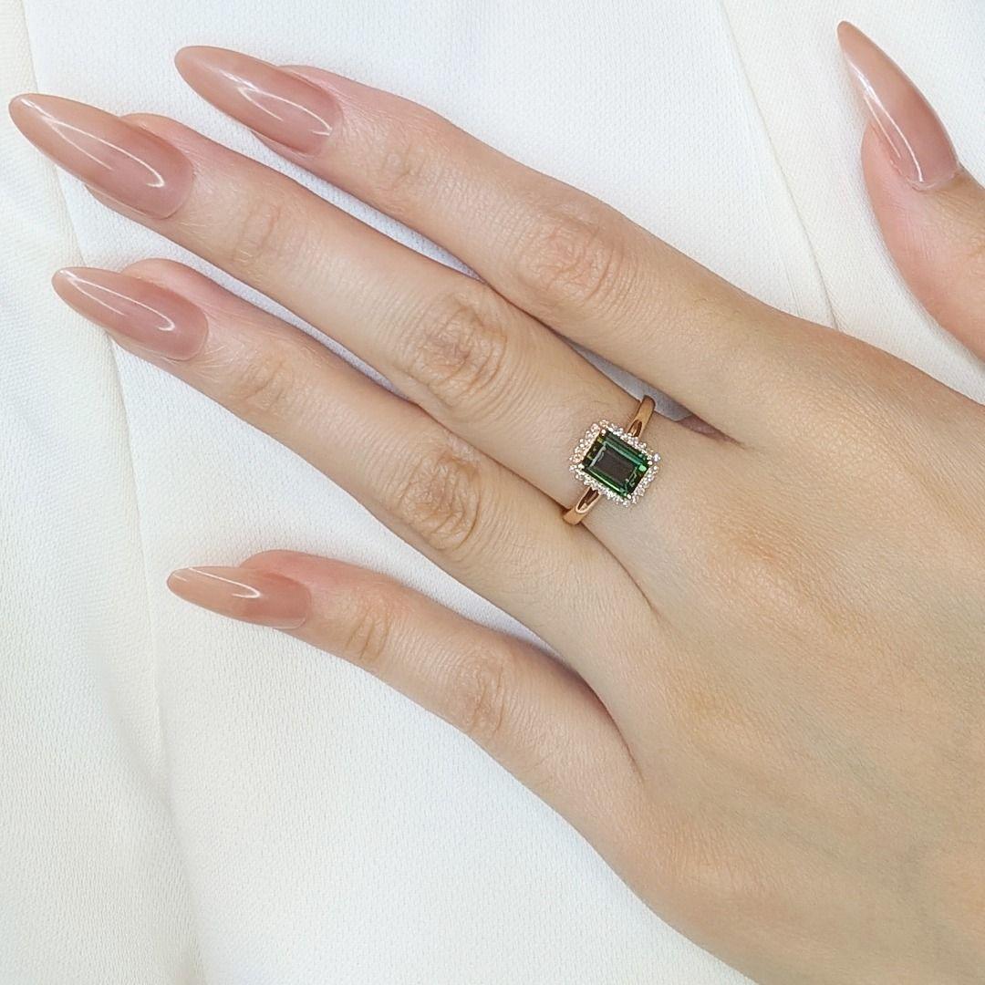 This stunning ring combines the timeless elegance of 18K yellow gold with the vibrant allure of a green emerald-cut tourmaline weighing 1.68ct. The centerpiece is beautifully accentuated by 26 round brilliant-cut natural diamonds, totaling 0.13ct,
