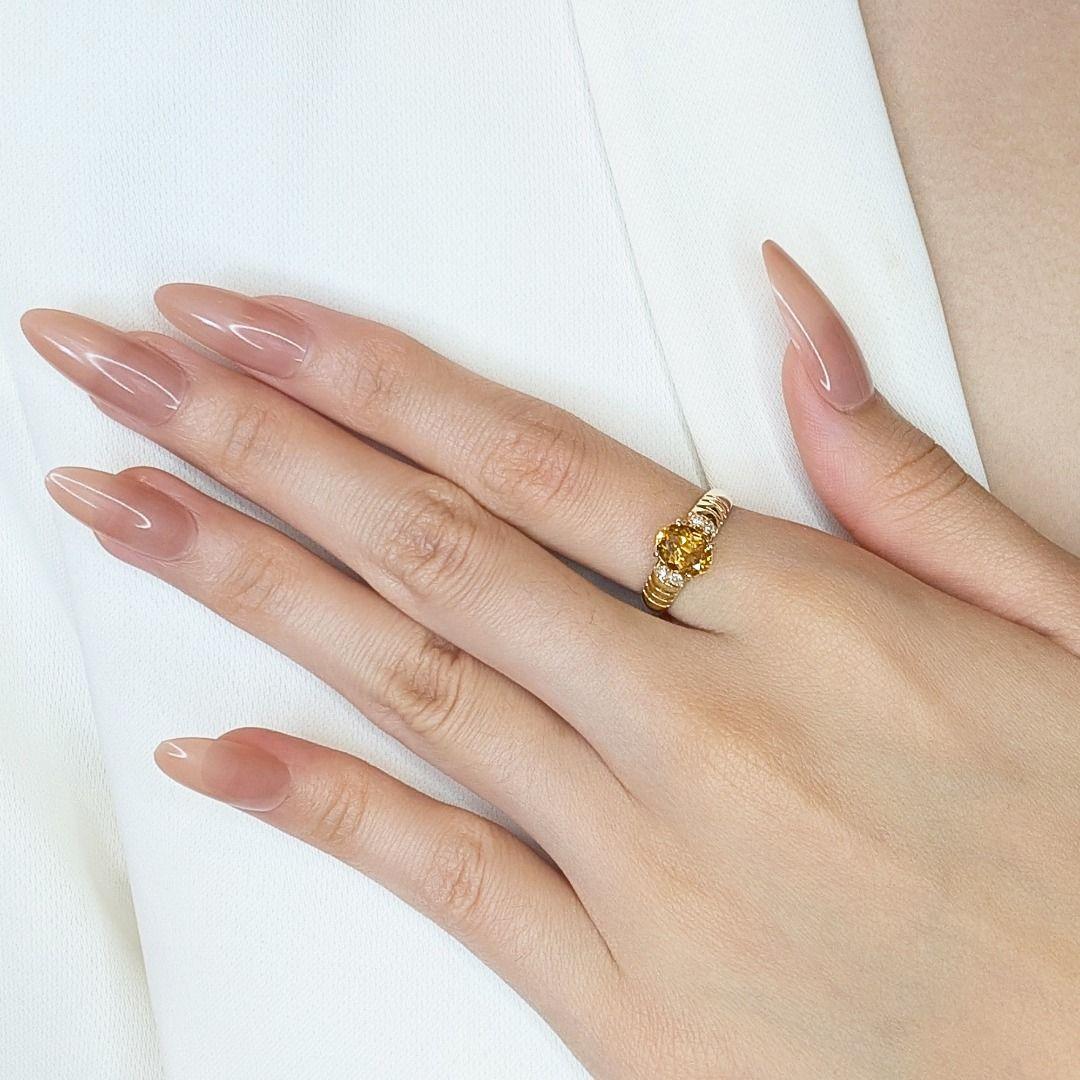 This exquisite ring, crafted from 18K yellow gold, showcases a stunning 1.8ct oval-shaped citrine at its center, radiating a vibrant orange hue. Accentuating the main stone are four natural round brilliant diamonds (0.06ct total, G color, VS