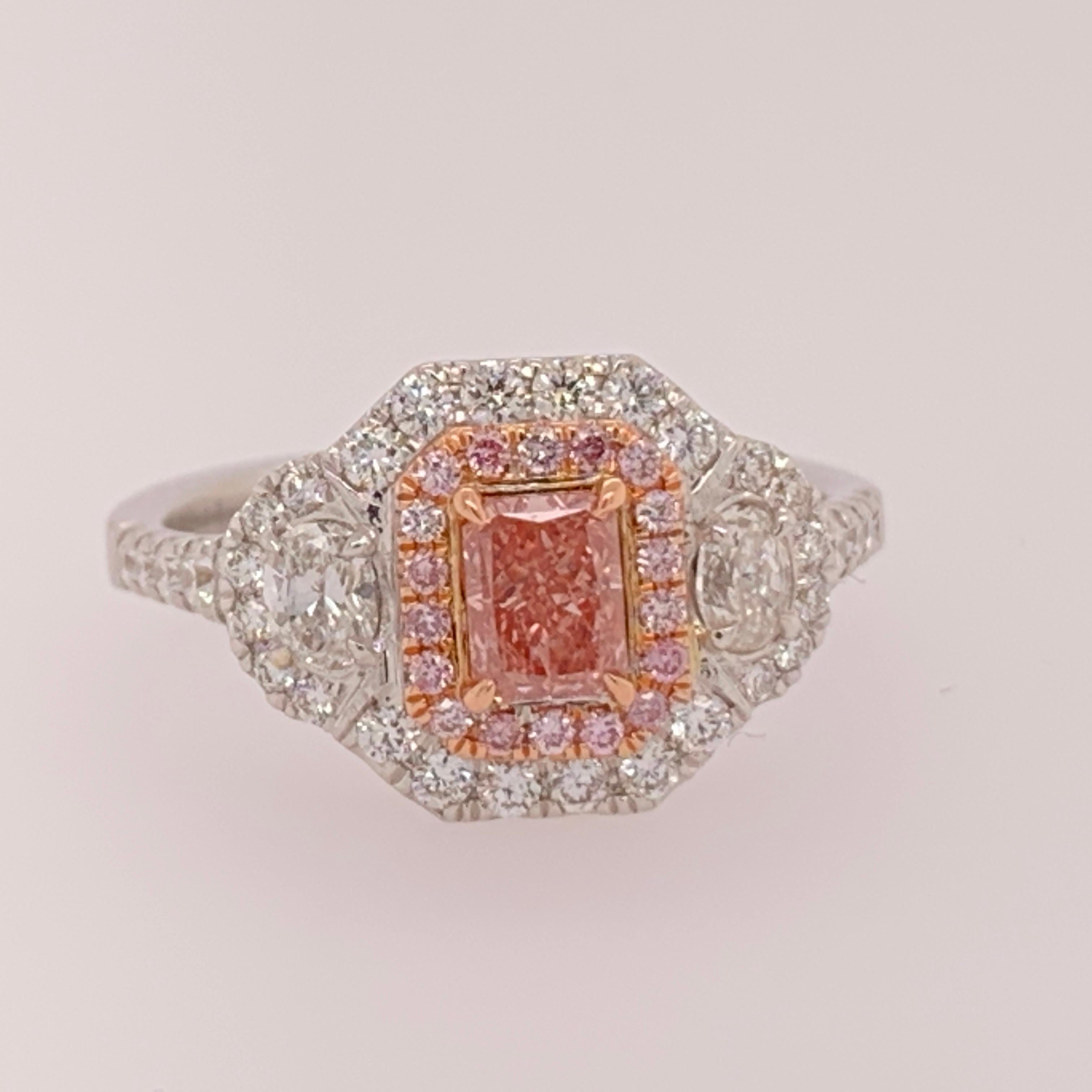 18k white gold Ladies Ring, SIZE 6.5.

Centerstone is a natural 0.40ct fancy orangy PINK rectangular radiant cut, GIA certified SI1 clarity. The surrounding Natural Round Brilliant pink diamonds (18) weigh 0.10 carats.

The ring contains 55